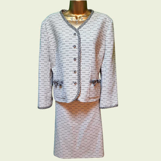 White and blue fleck suit with bow detail on a beige background