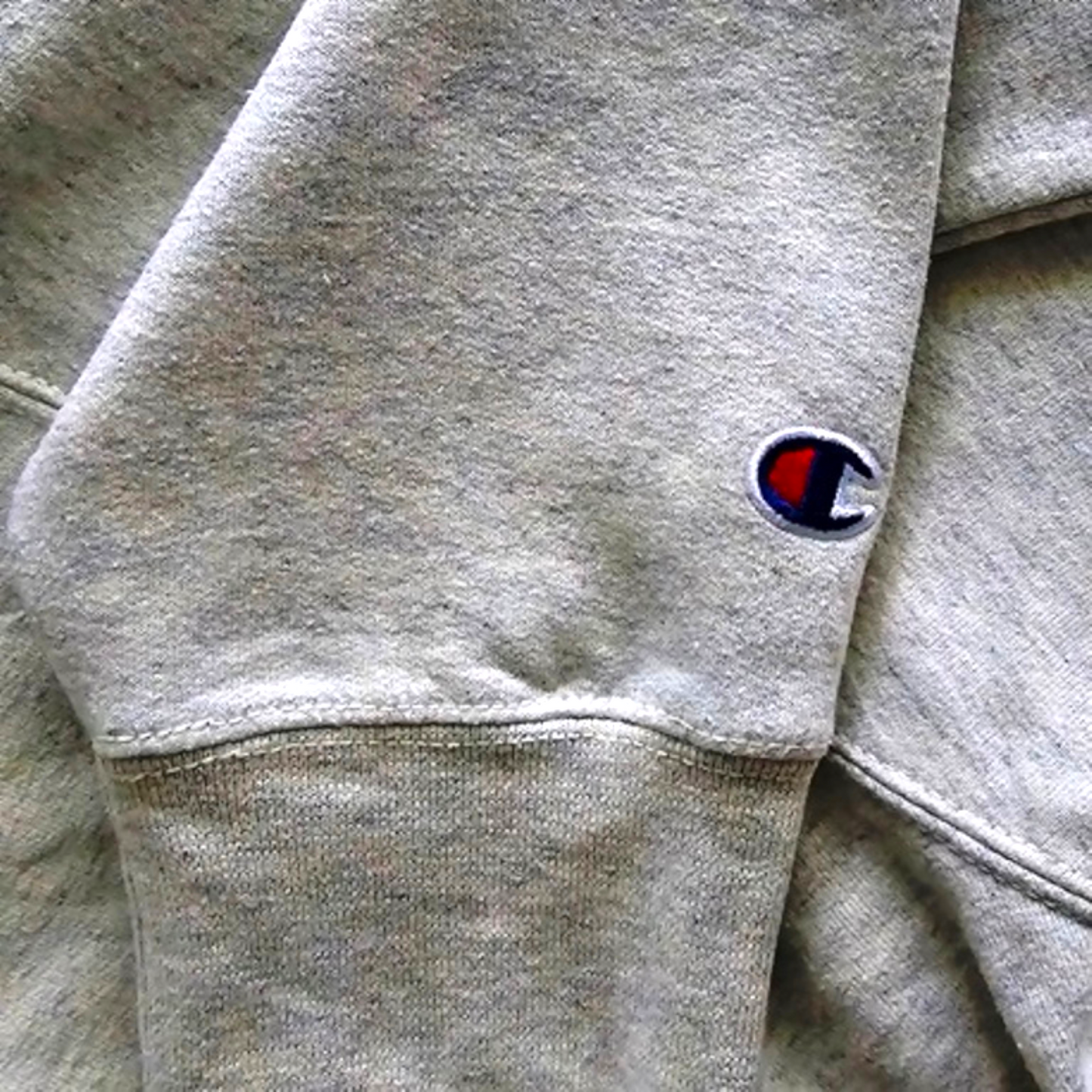 Close-up of gray hoodie with a brand logo on the waistband.