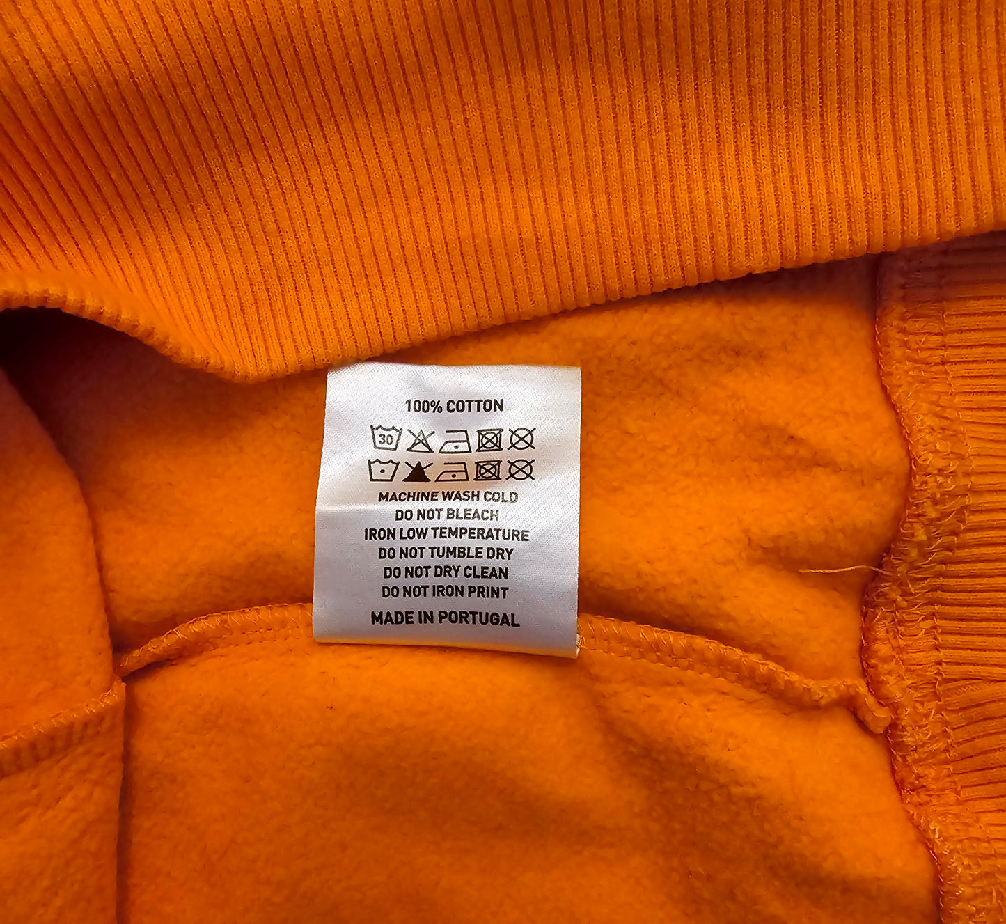 Clothing label on an orange fabric with washing instructions.