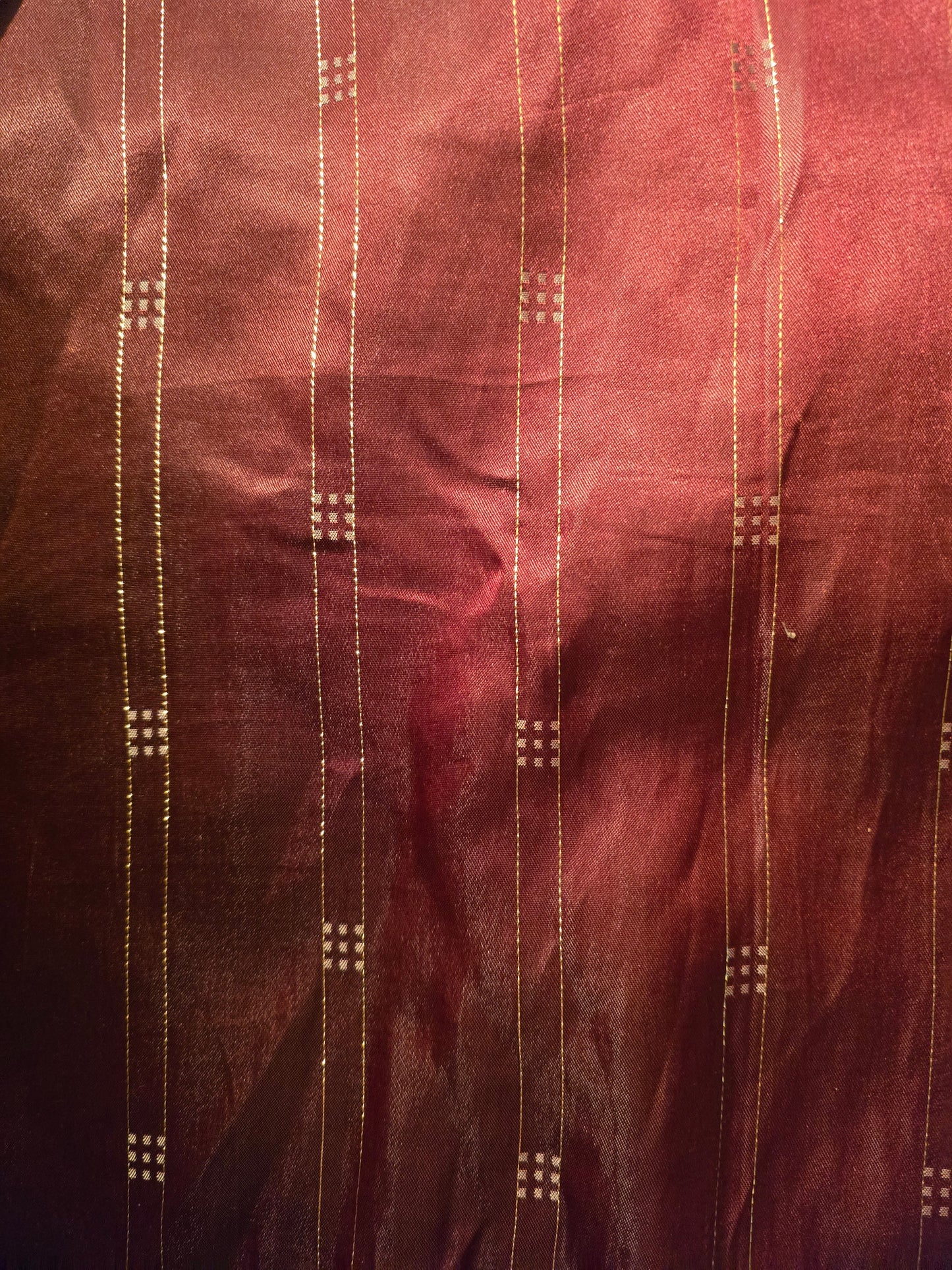 Close-up of maroon fabric with gold thread patterns