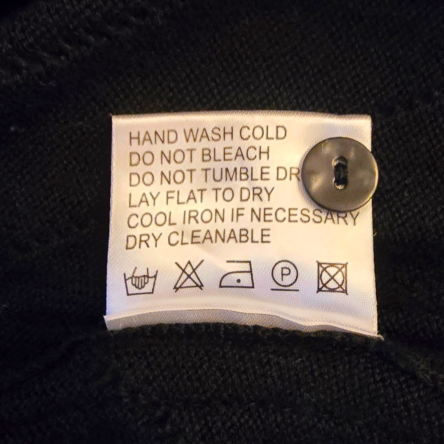 Clothing label with washing instructions on a black fabric background