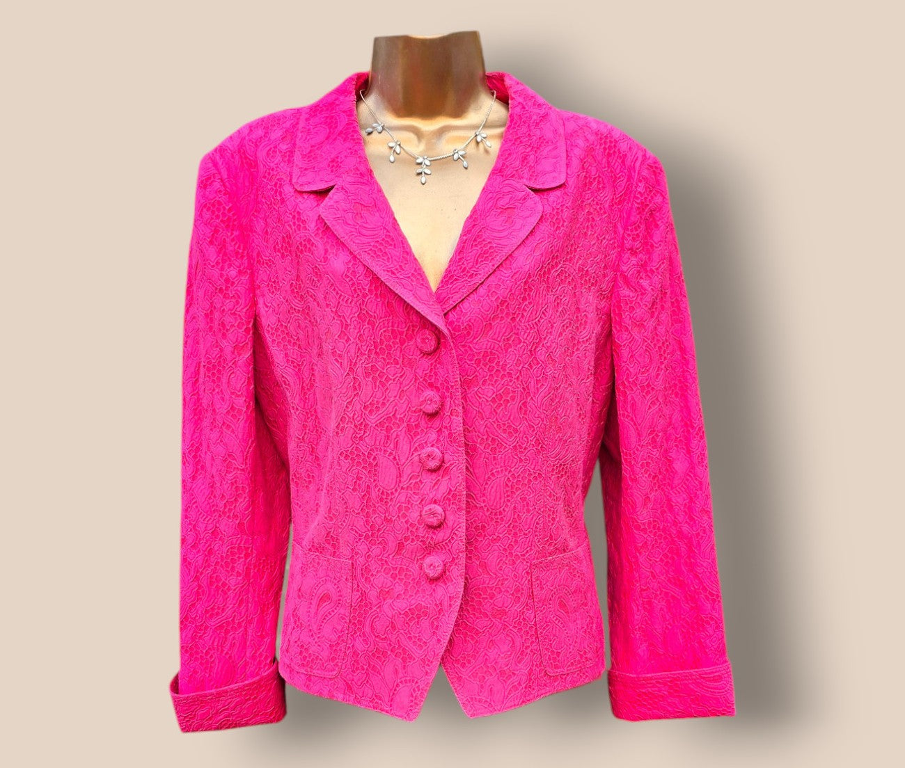 Pink textured jacket on a mannequin against a beige background