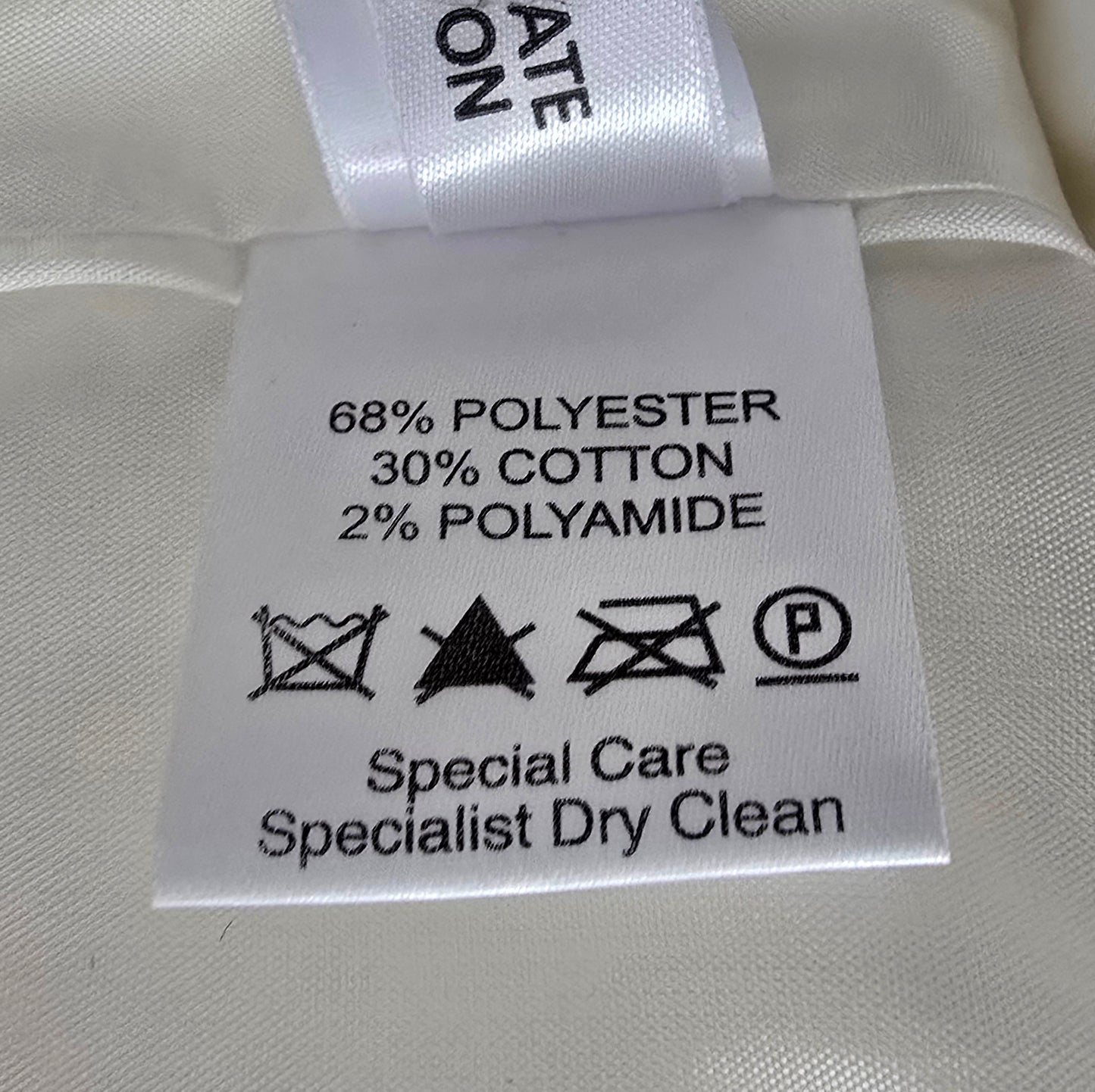 Clothing label with care instructions and material composition on a white fabric background