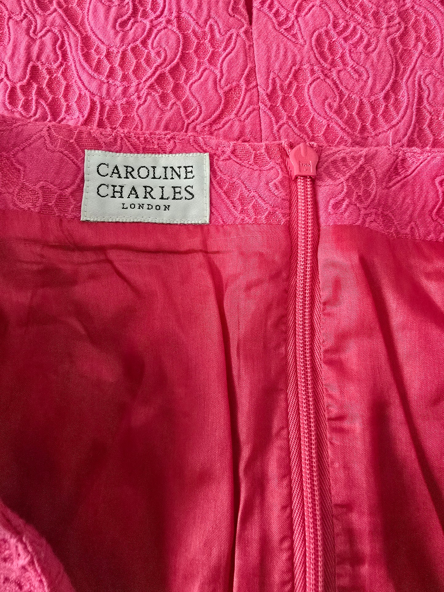 Pink fabric with a visible brand label on a textured pink background