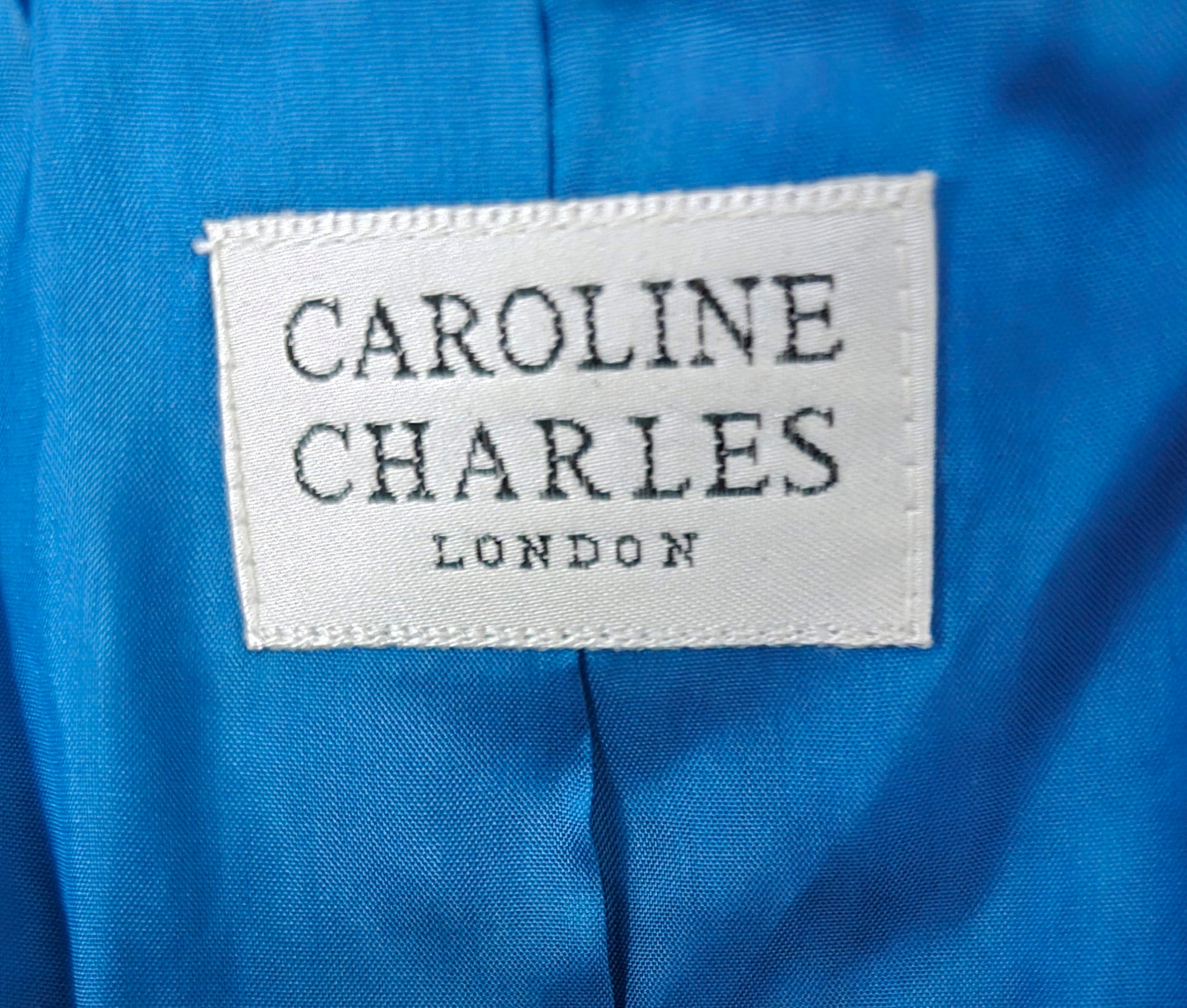 Label with 'Caroline Charles London' on a blue fabric background