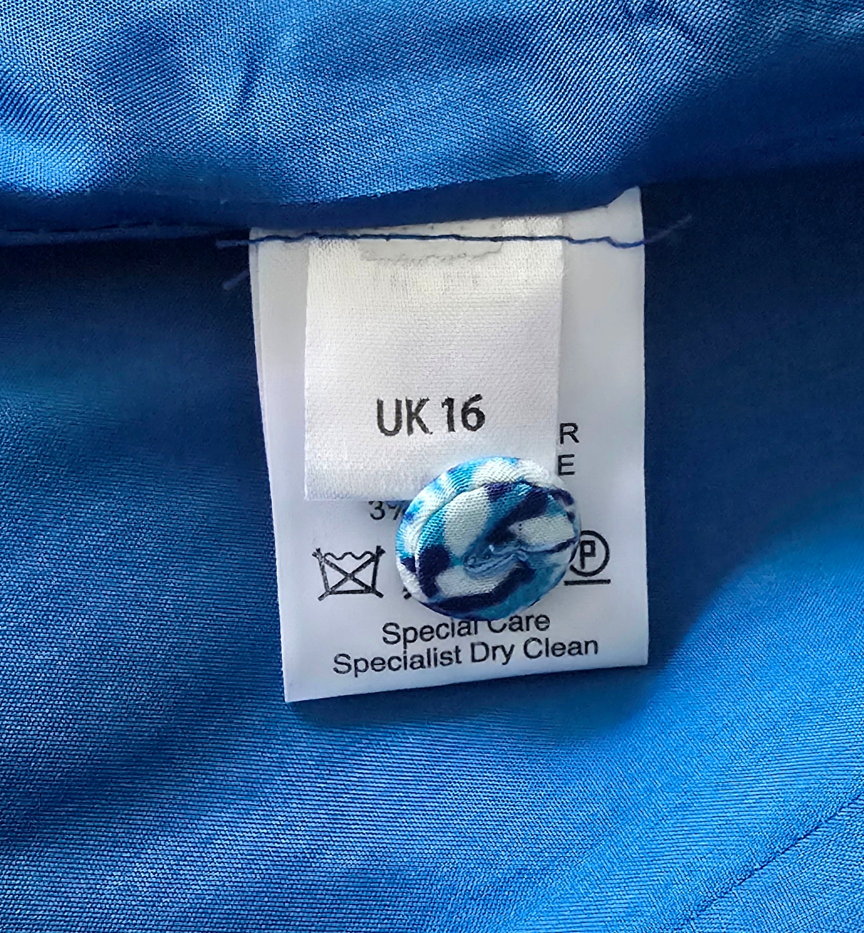 Clothing label with care instructions on a blue fabric background