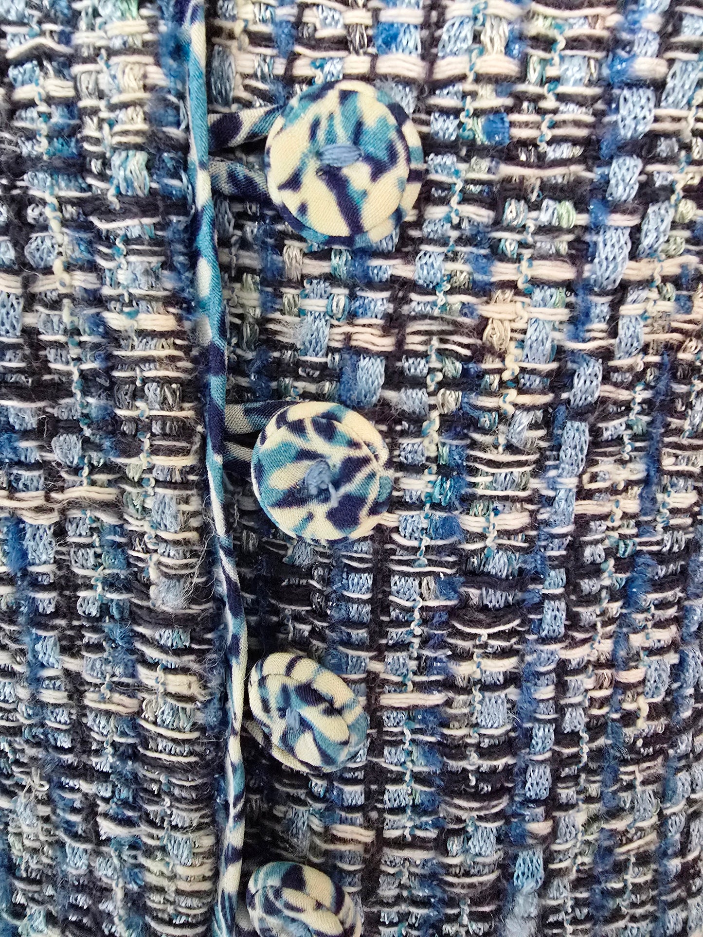 Close-up of a textured fabric with blue and white patterned buttons.
