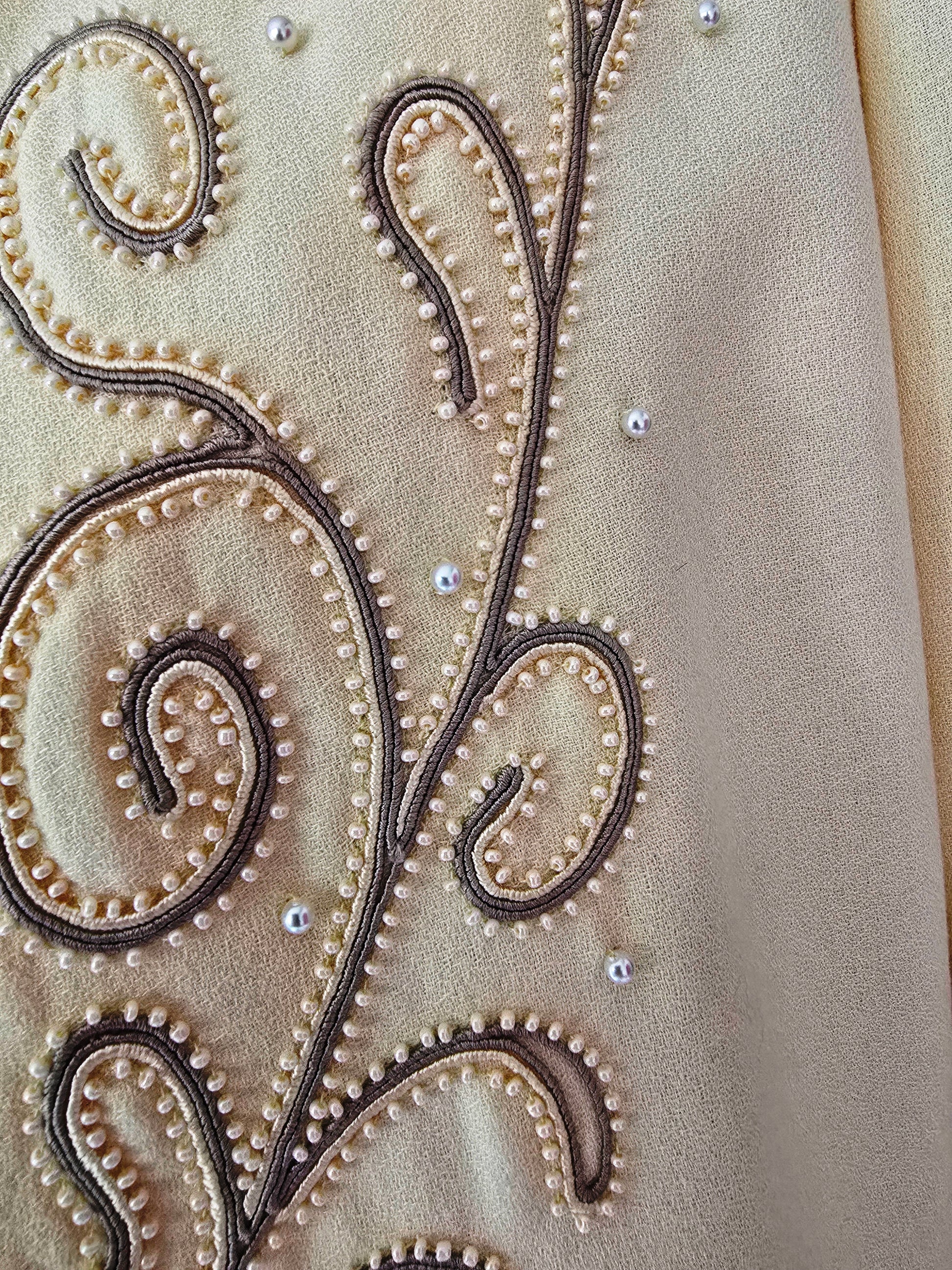Close-up of intricate beadwork on a yellow fabric surface