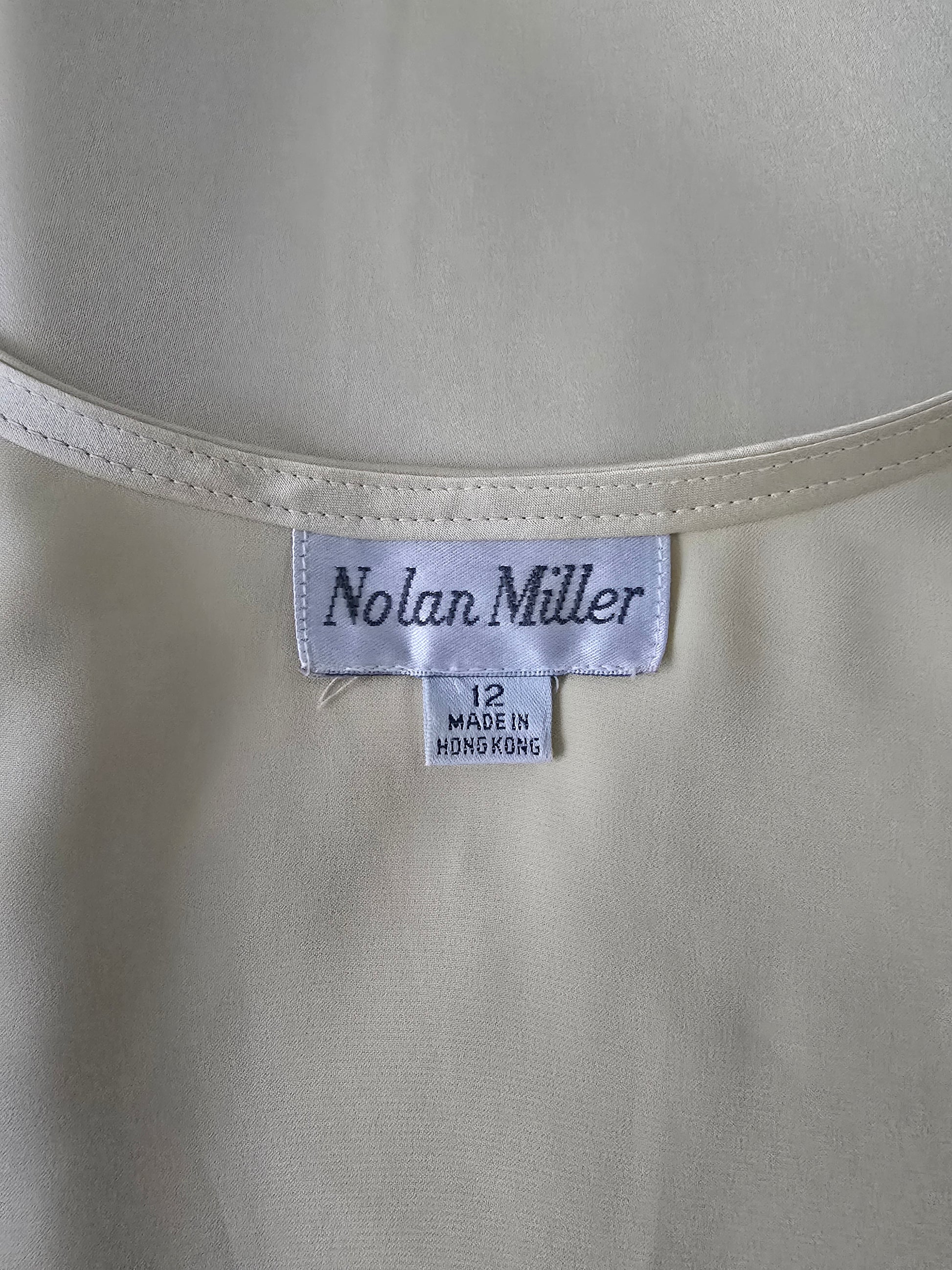 Nolan Miller label on a beige fabric background