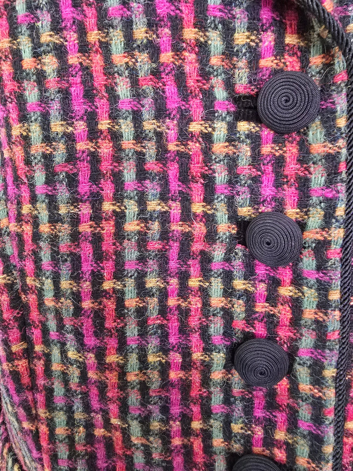 Close-up of a multicolored fabric with black buttons on a plaid pattern.