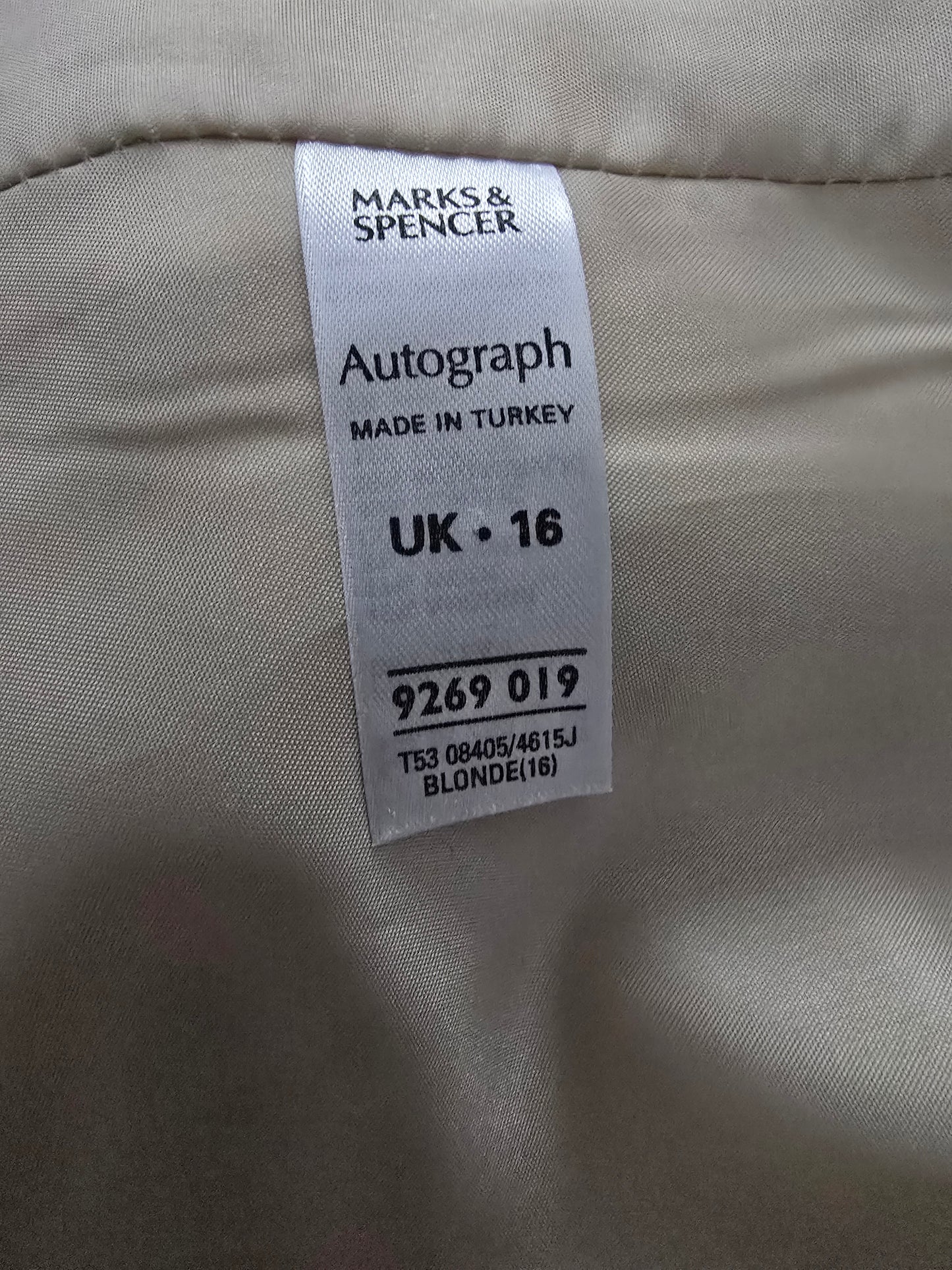 Clothing label on a beige fabric background with 'Marks & Spencer' branding.