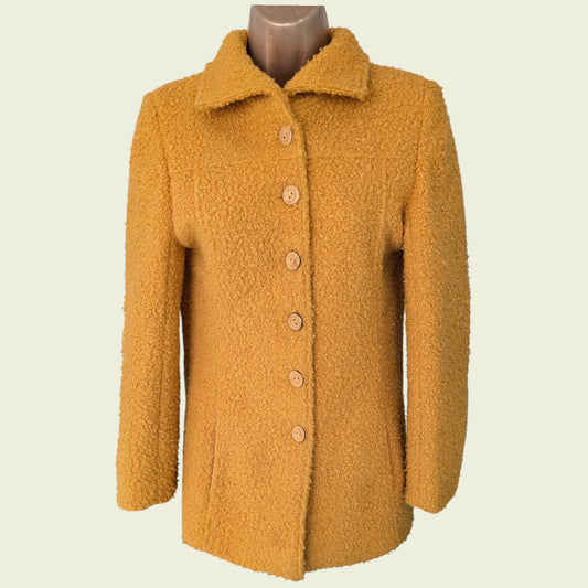 Mannequin wearing mustard coloured jacket on beige background