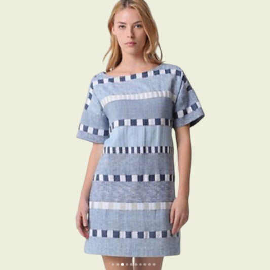 Woman wearing a blue and white striped dress on a beige background