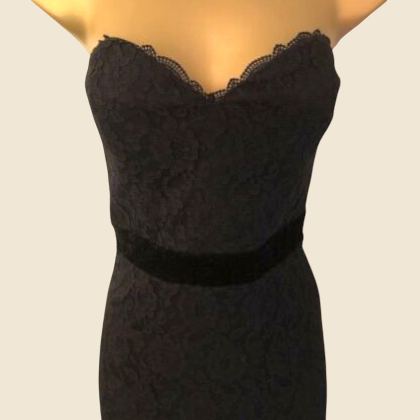 Black lace dress on a mannequin against a plain background