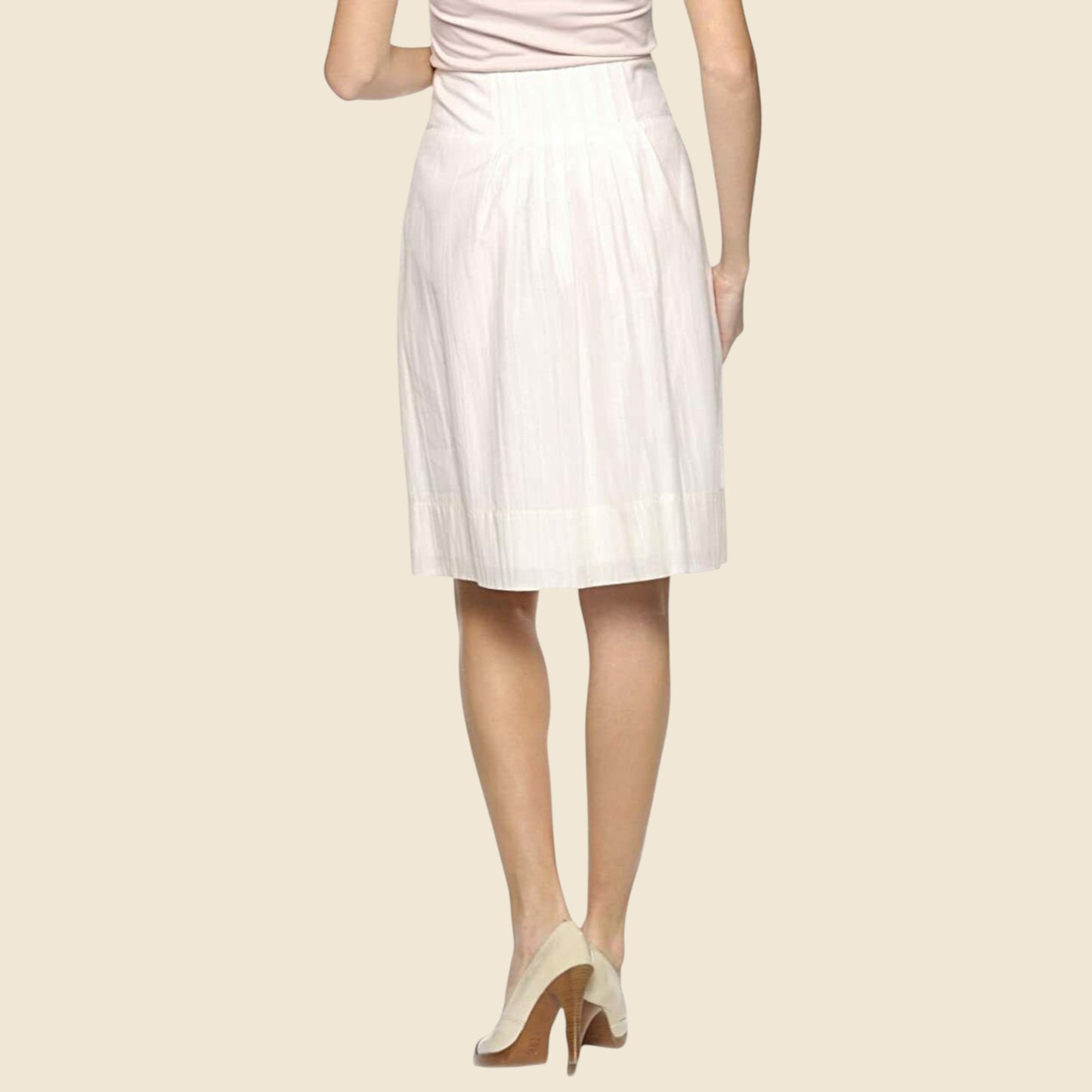 Cream pleated skirt worn by a person on a beige background