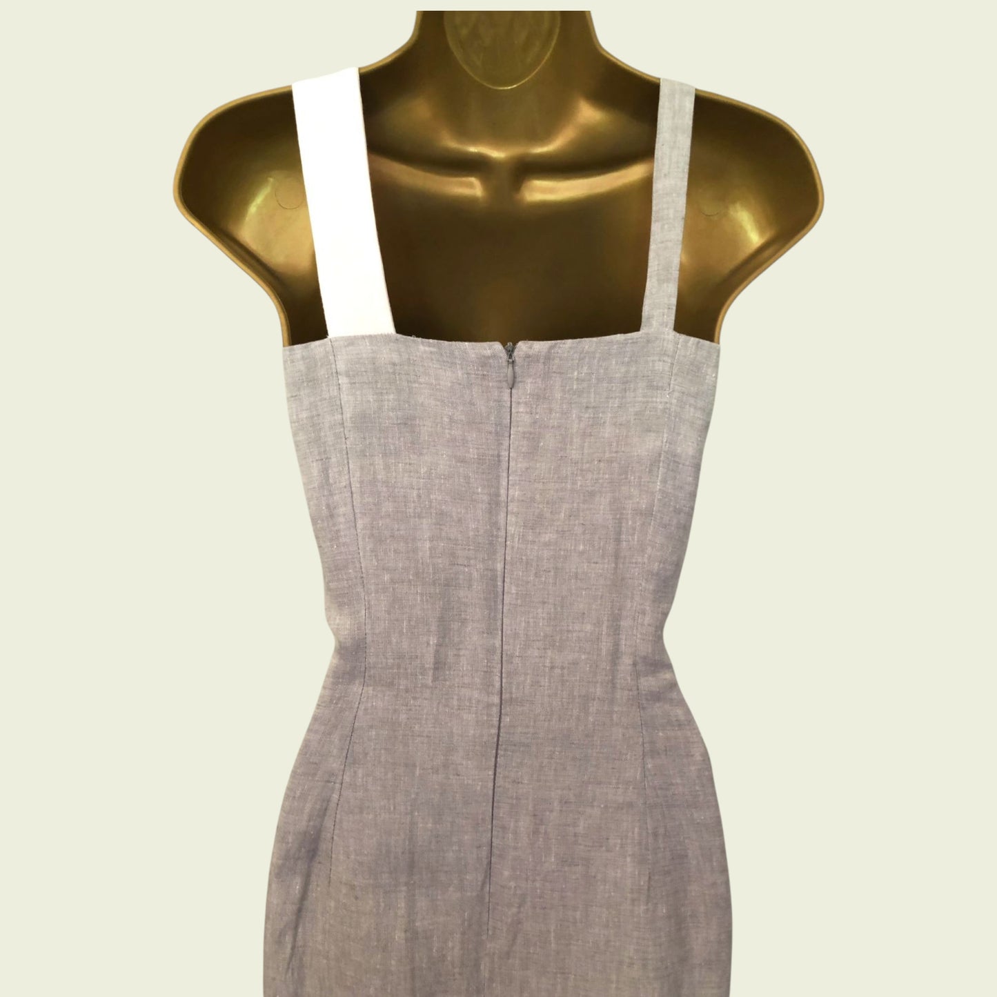 Gray dress on a gold mannequin against a beige background