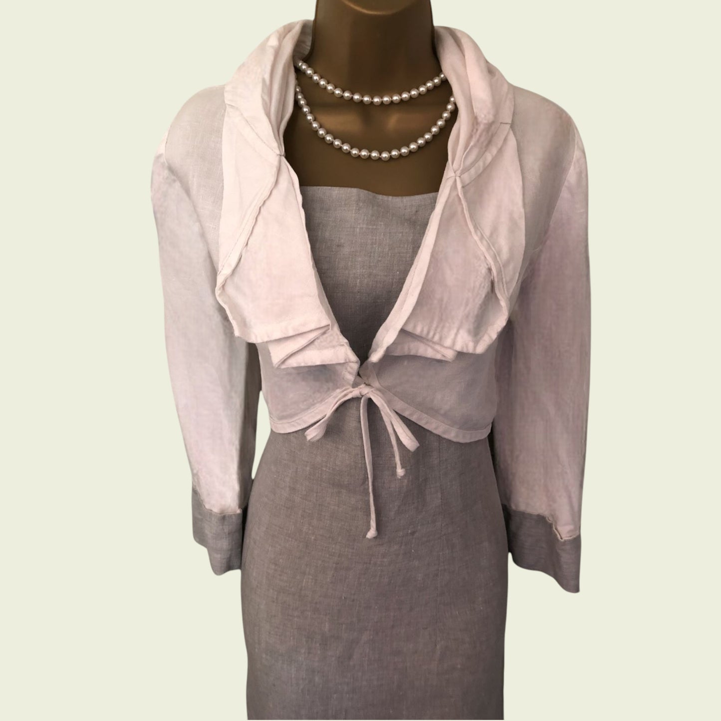 Mannequin wearing a gray dress with a matching bolero on a light background