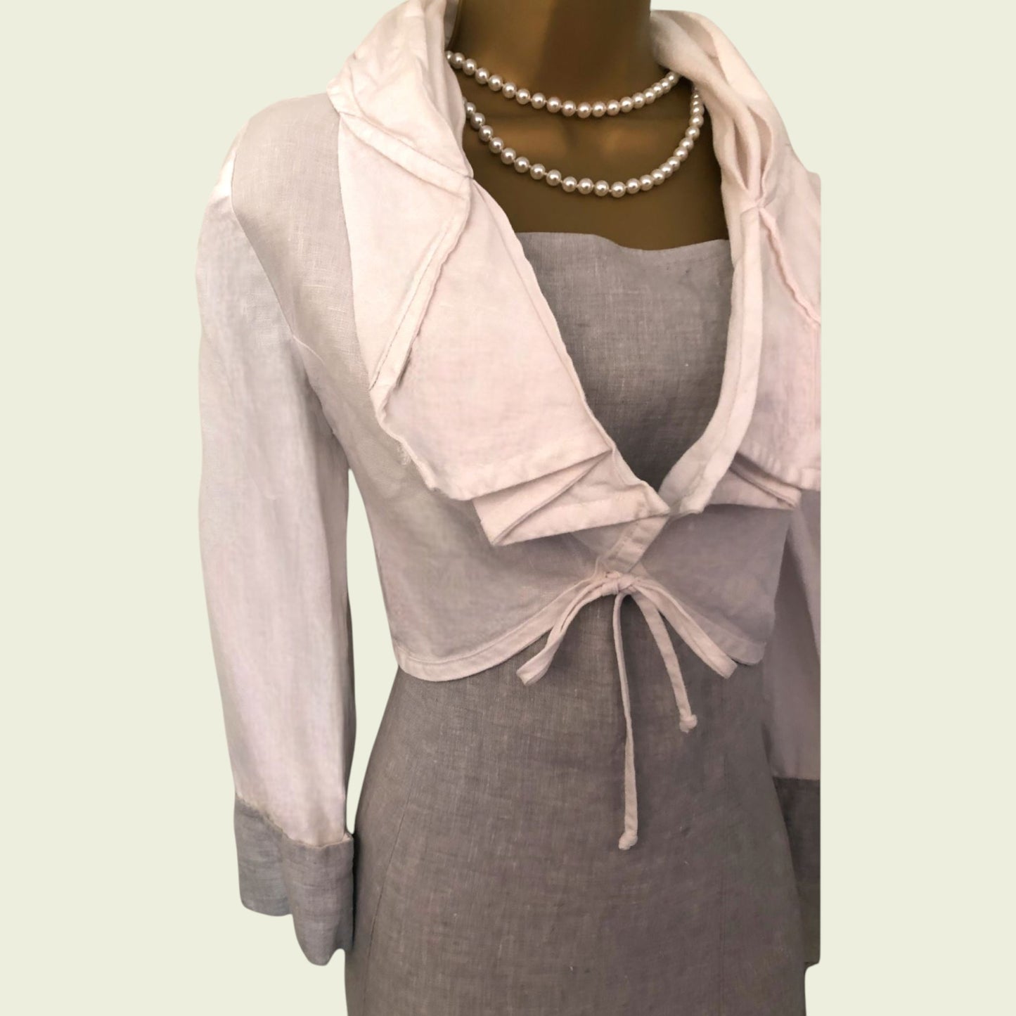 Mannequin wearing a gray dress with a pink bolero on a light green background