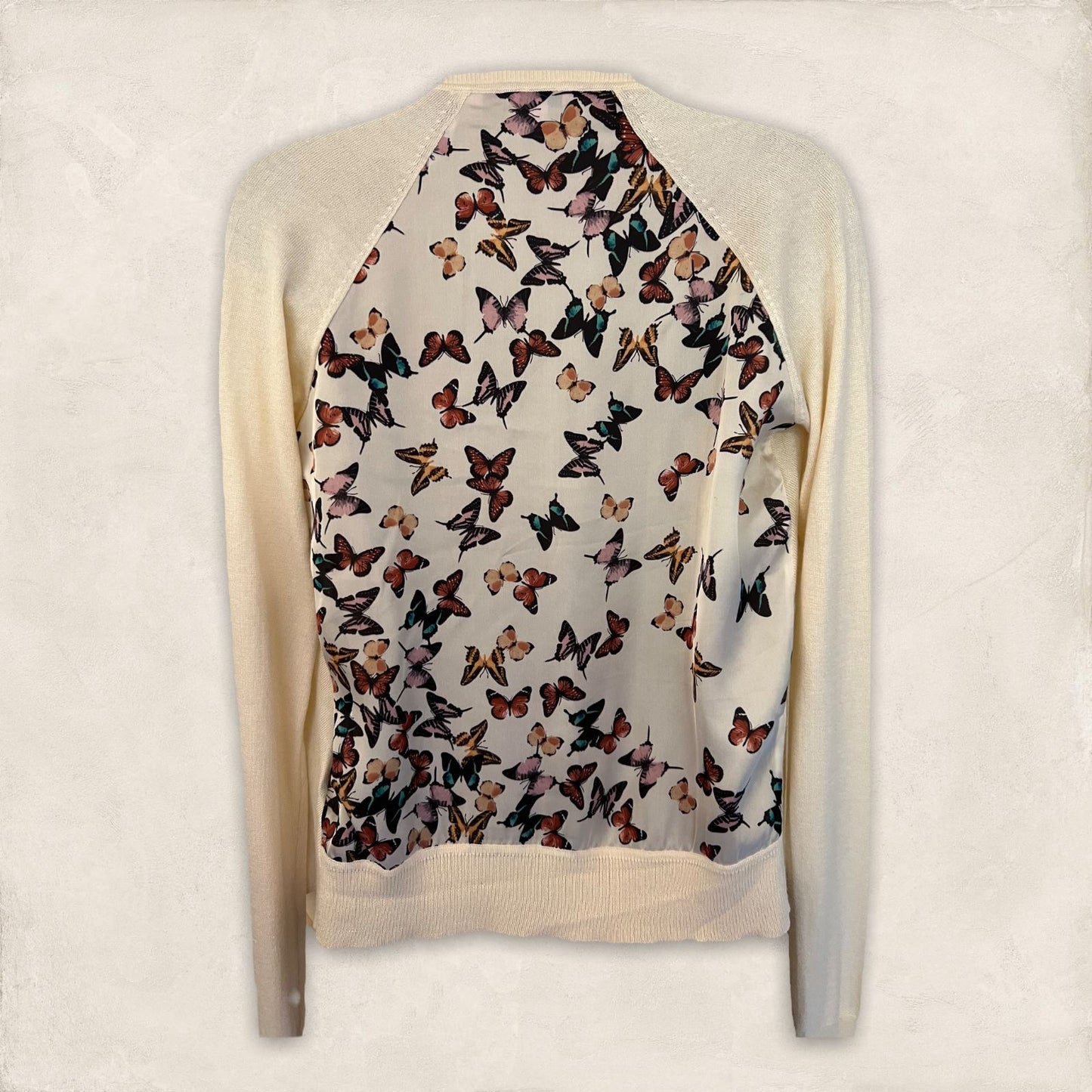 Sweater with butterfly pattern on the back against a plain background