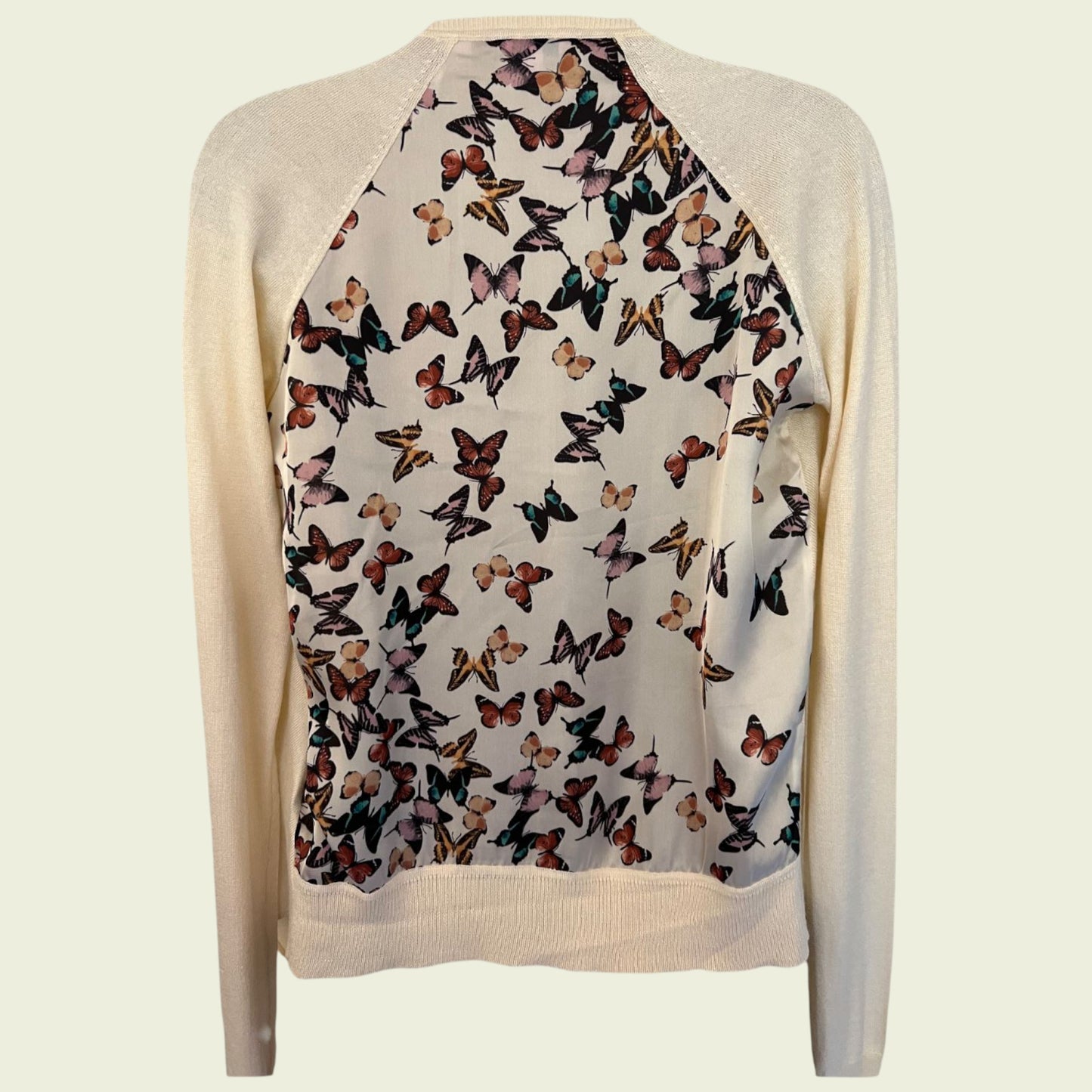 Beige cardigan with butterfly pattern on a light beige background
