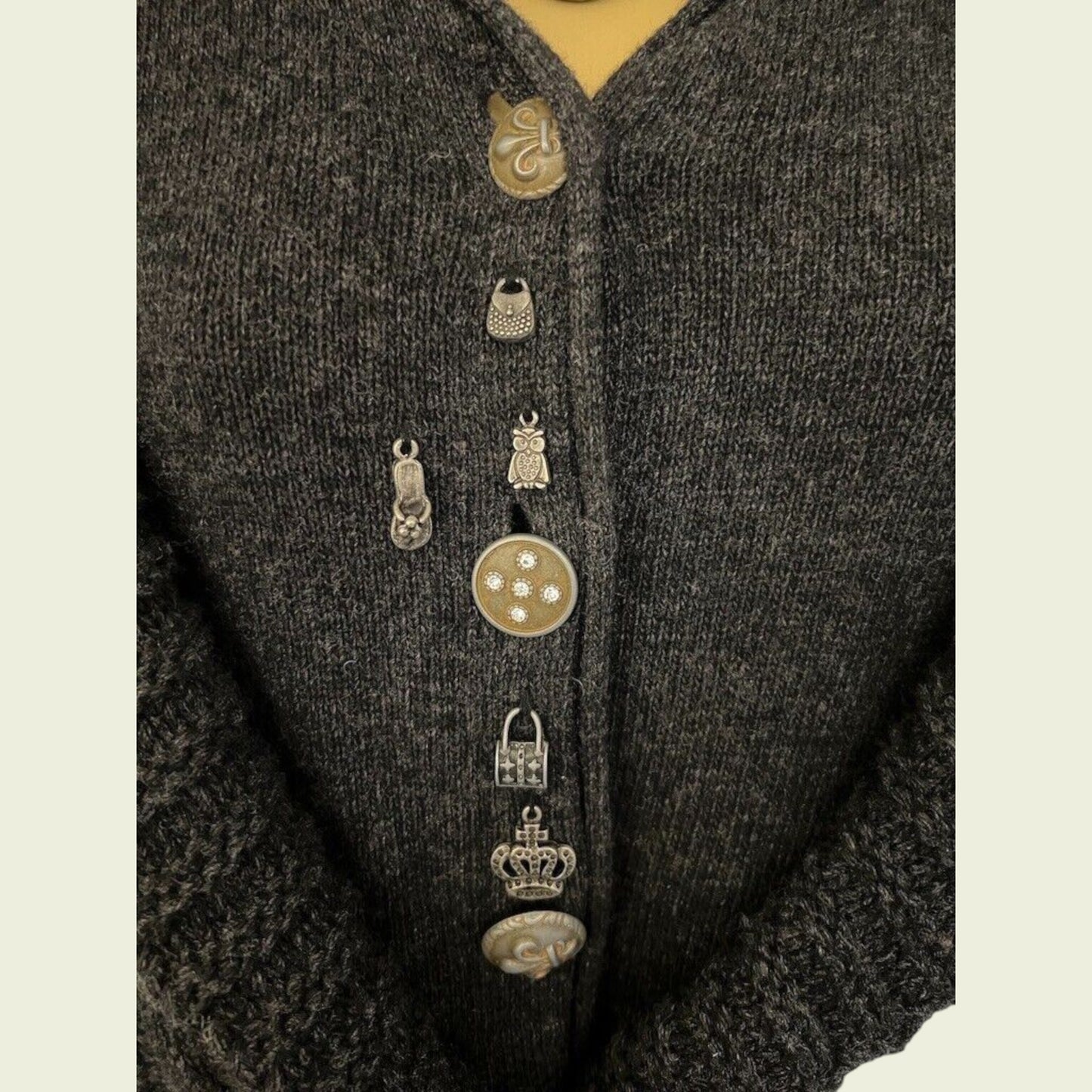Close-up of a dark textured garment with decorative buttons on a beige background