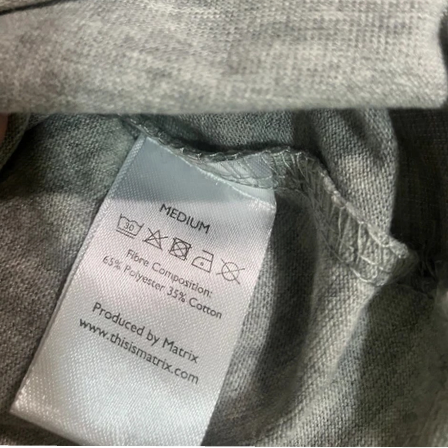 Clothing label on a gray garment with fabric texture