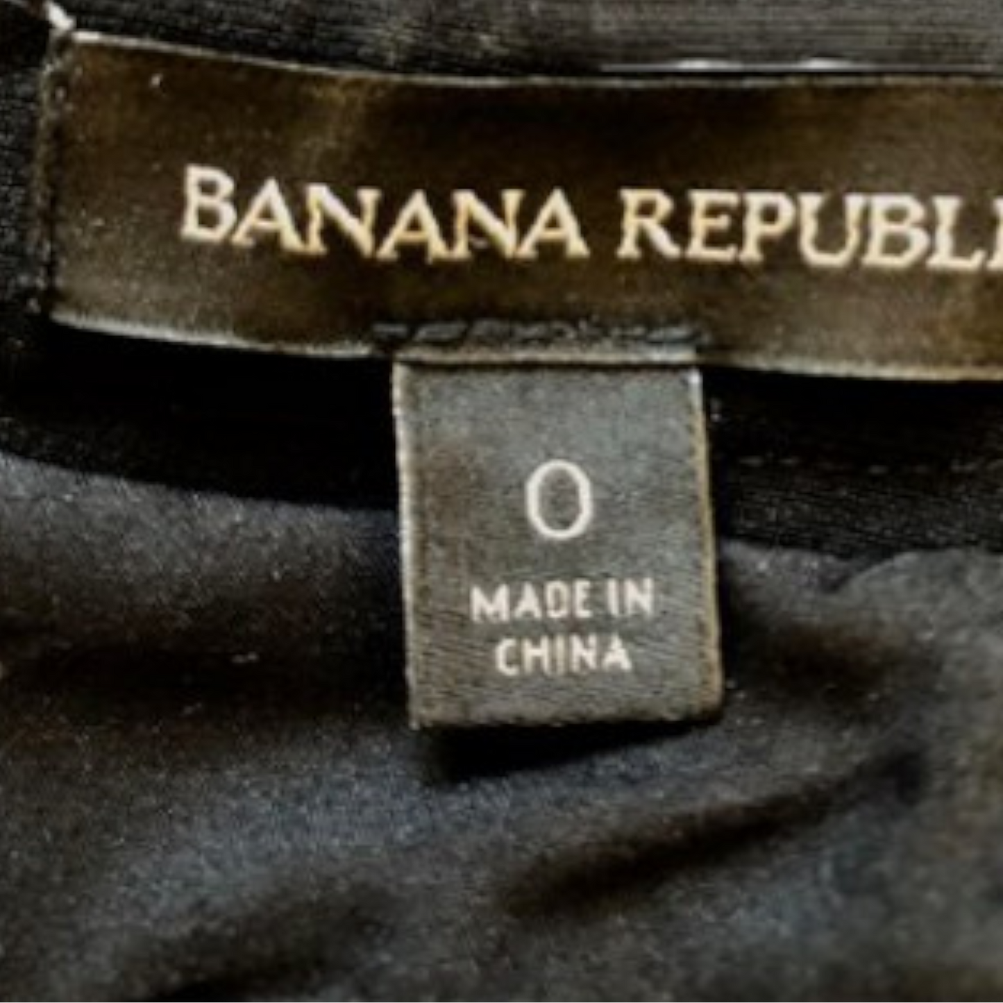 Close-up of a Banana Republic garment label and size tag on black fabric, showing 'BANANA REPUBLIC' and '0 MADE IN CHINA'.