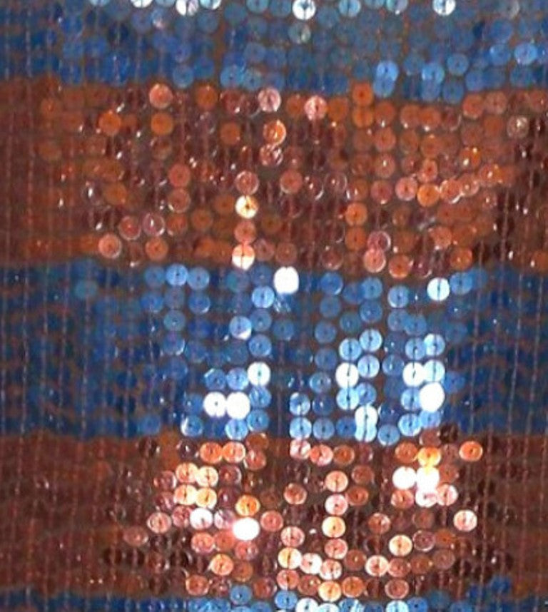 Close-up of a sequined fabric with blue, orange, and white colors.