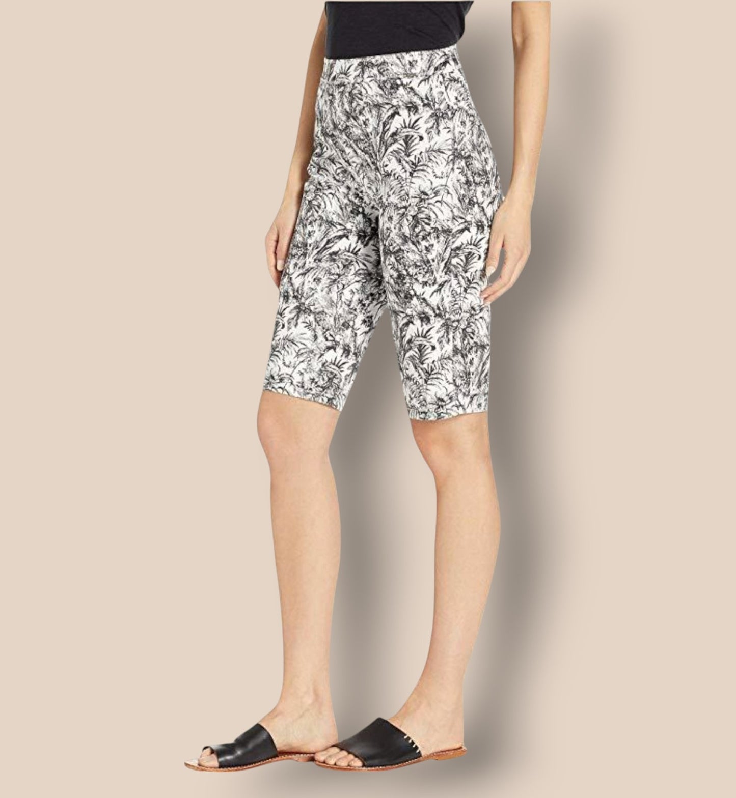 Person wearing black and white floral capri pants on a beige background