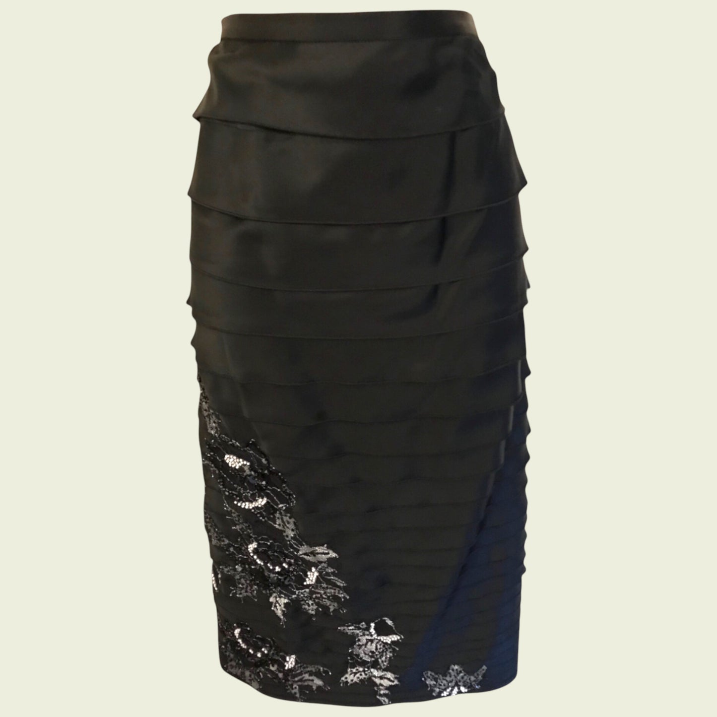 Black skirt with floral lace detail on a beige background
