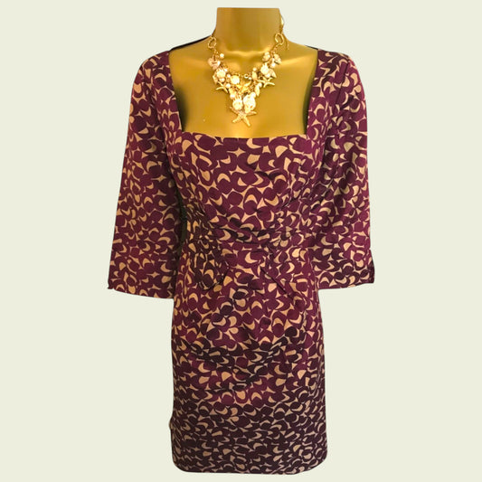 Purple patterned dress on a mannequin with a gold necklace against a beige background