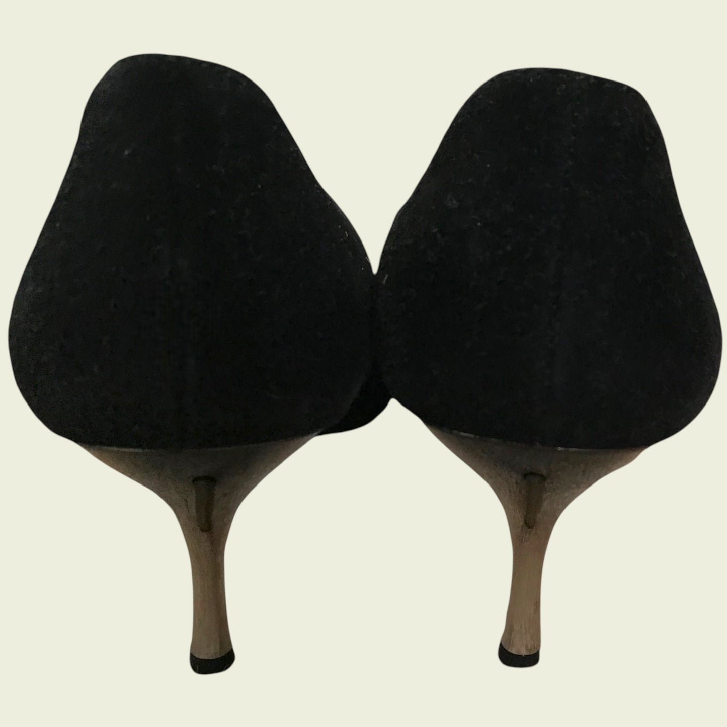 Back of black suede shoes showing heel on beige background