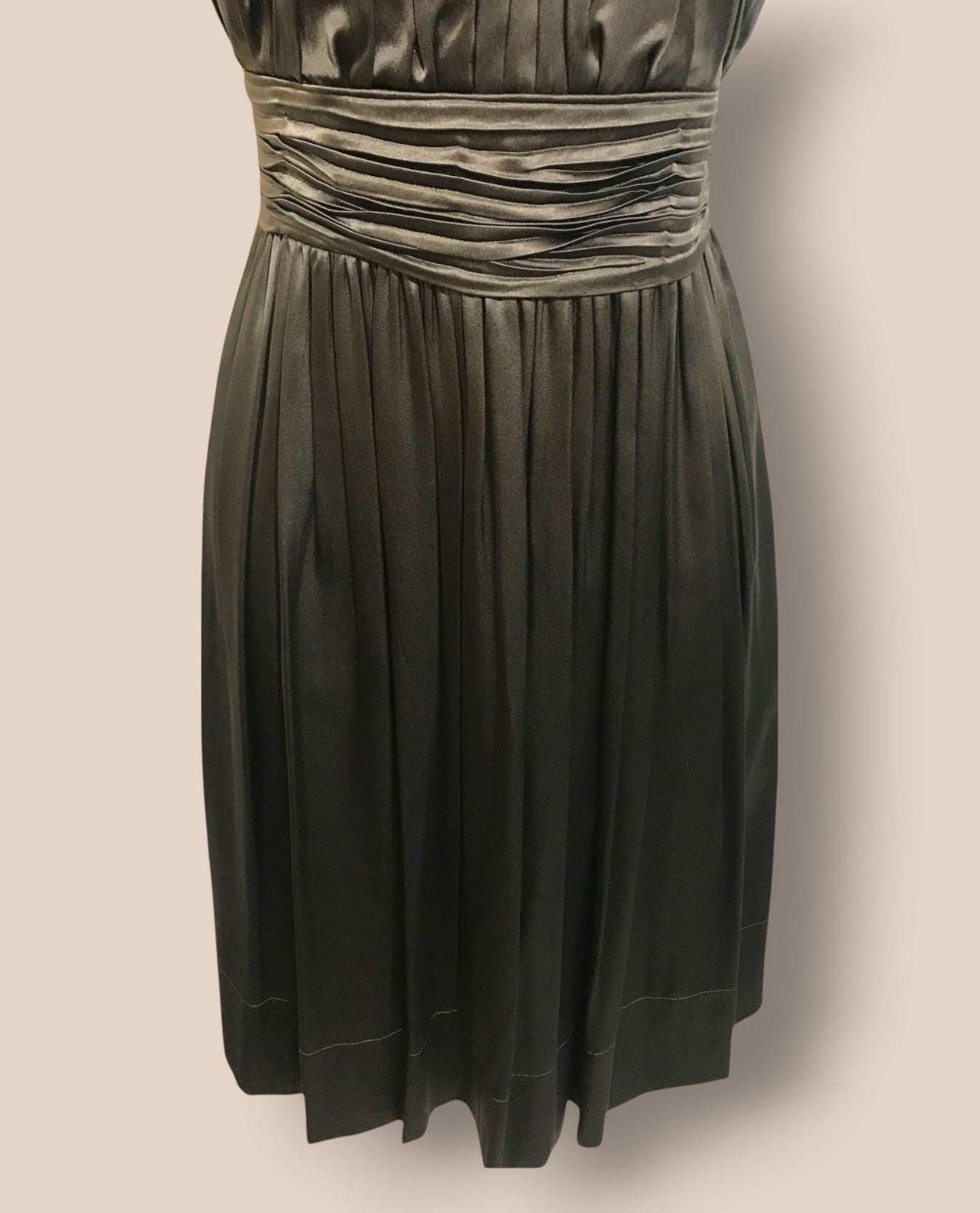 Dark green dress with pleated waist on a beige background