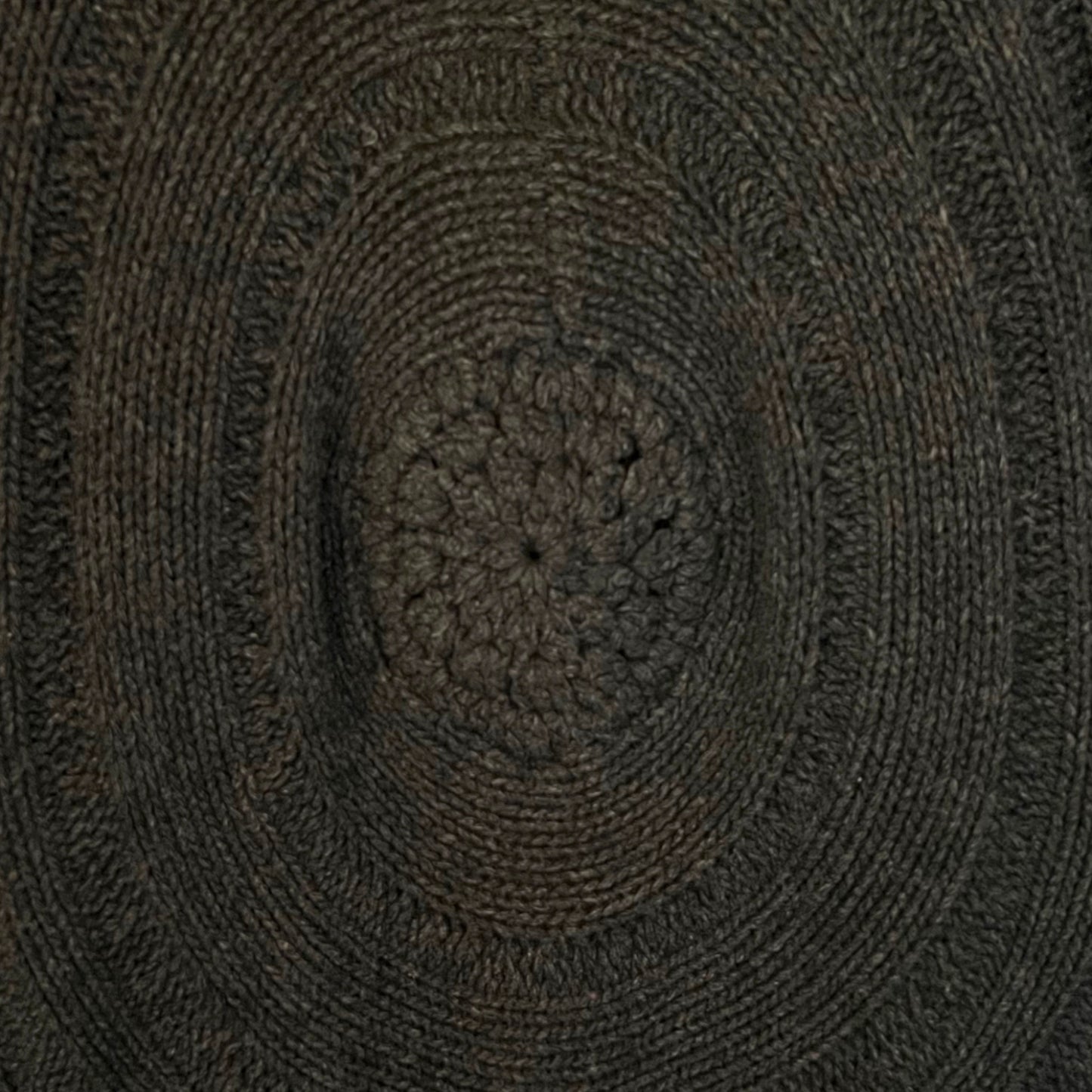 Close-up of a textured brown circular design with concentric patterns on brown cardigan