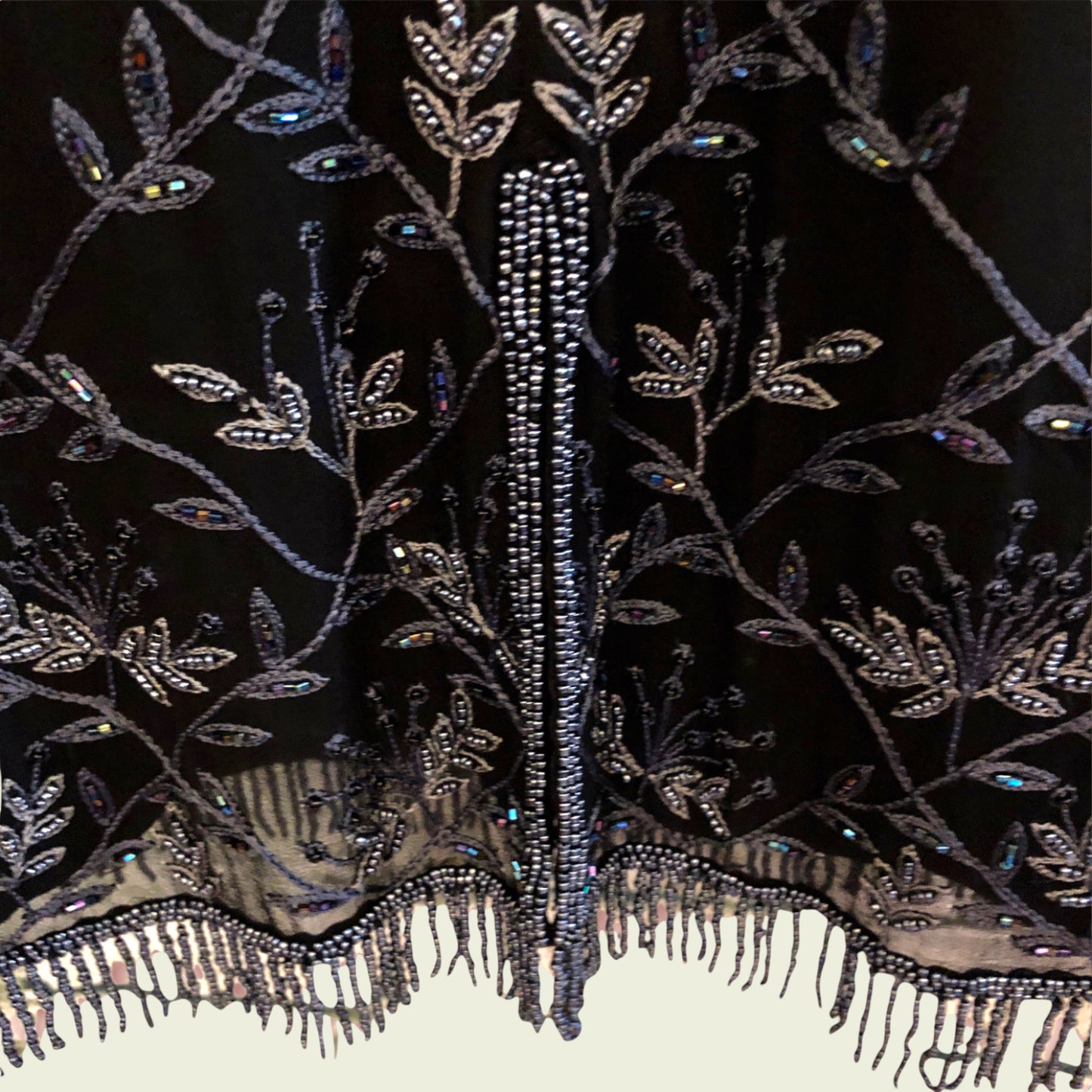 Close-up of an intricately beaded and embroidered fabric with floral patterns on a dark background.