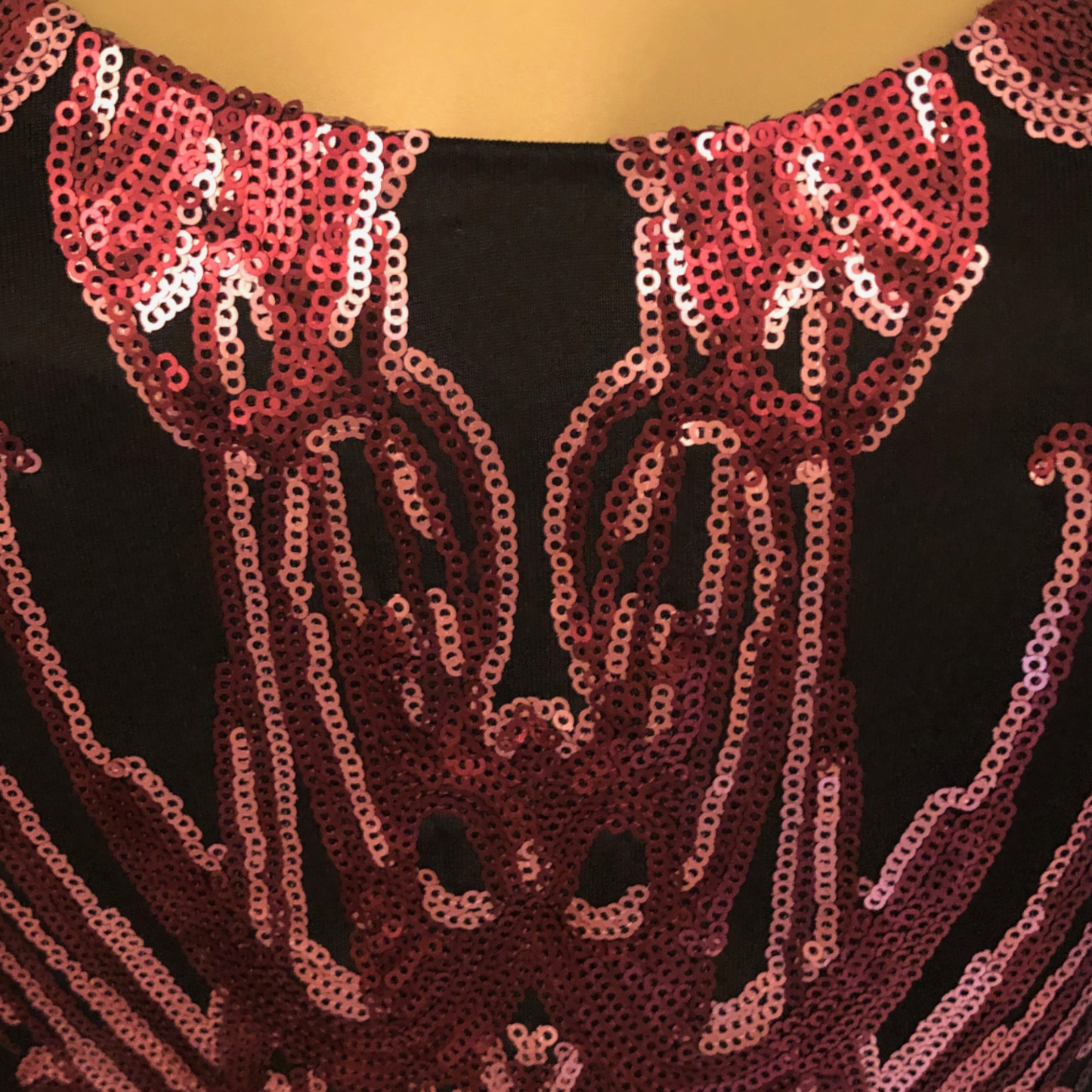 Close-up of a sequined garment with pink and black pattern on a dark background