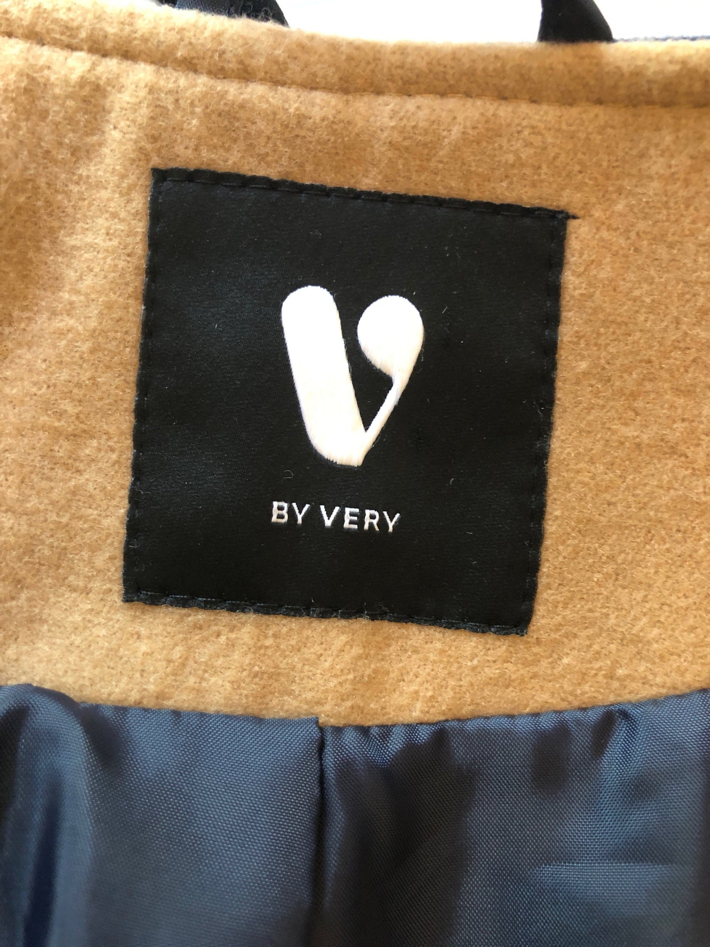 Close-up of a brown fabric surface with a black label featuring a white logo and text.