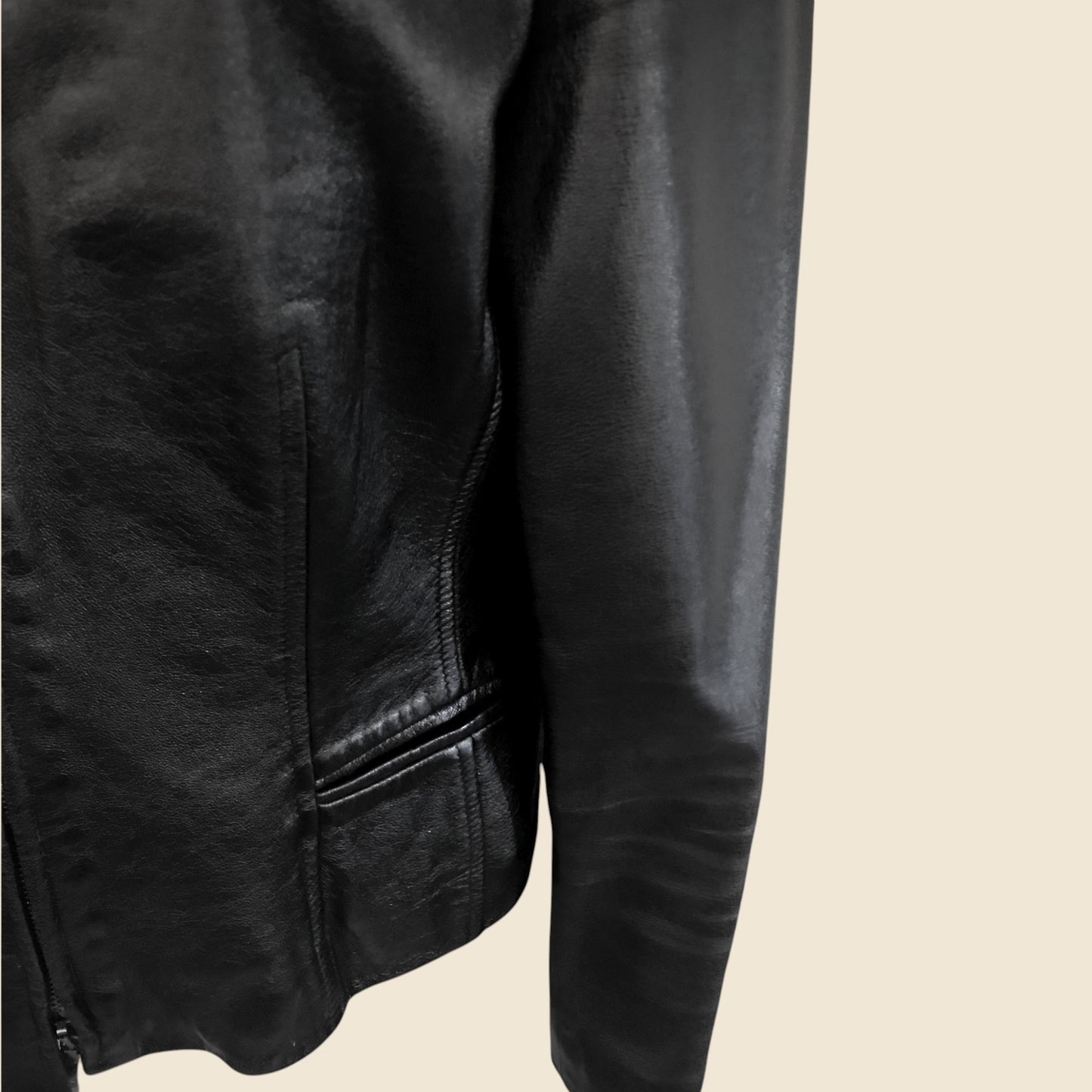 Close-up of a black leather jacket on a beige background