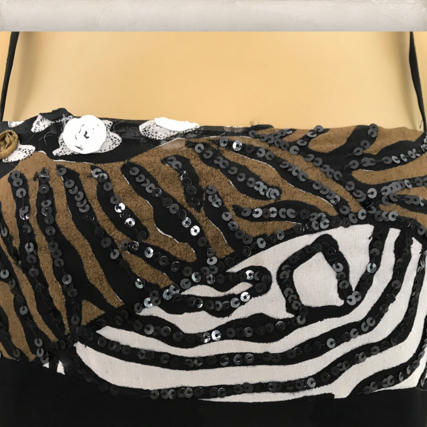 Zebra print with sequins on dress top on a mannequin against a beige background