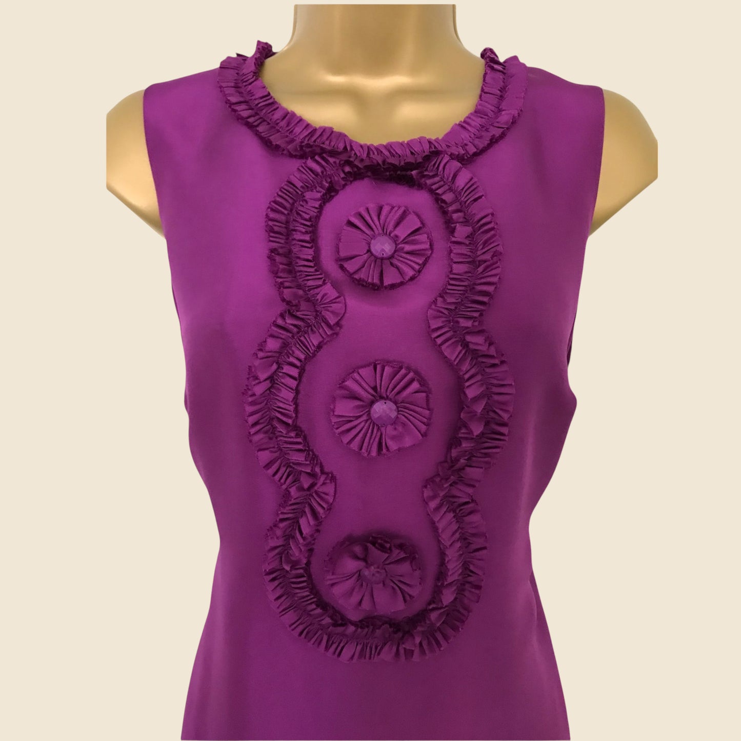 Purple sleeveless top with decorative ruffles on a beige background