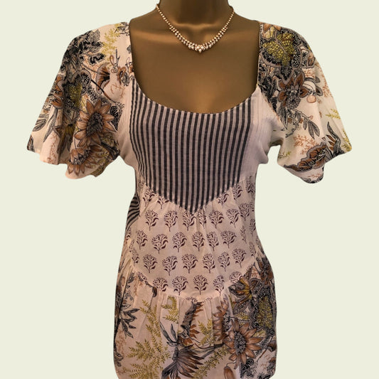 Mannequin wearing a floral-patterned top with a striped bodice on a beige background
