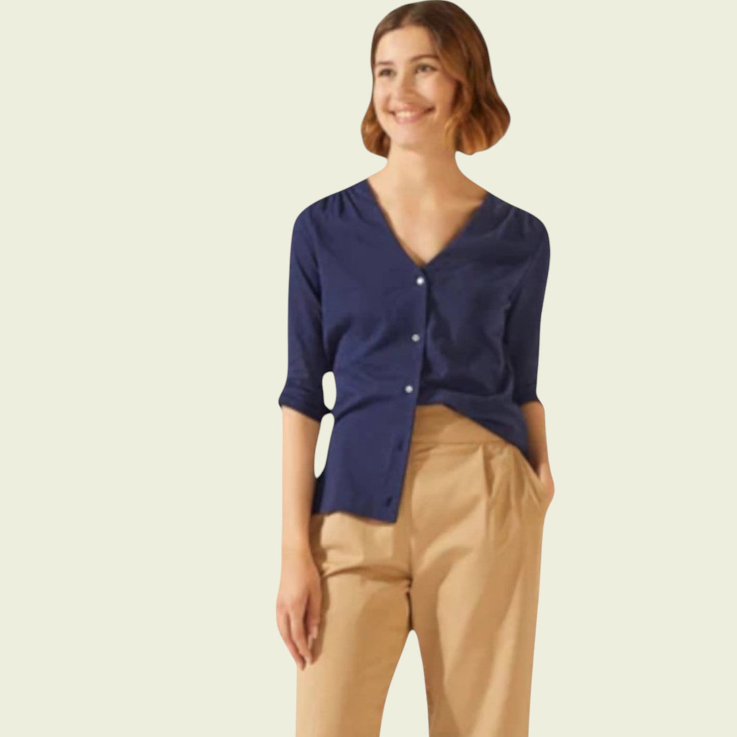 Woman wearing a navy blue cardigan and beige pants on a light background