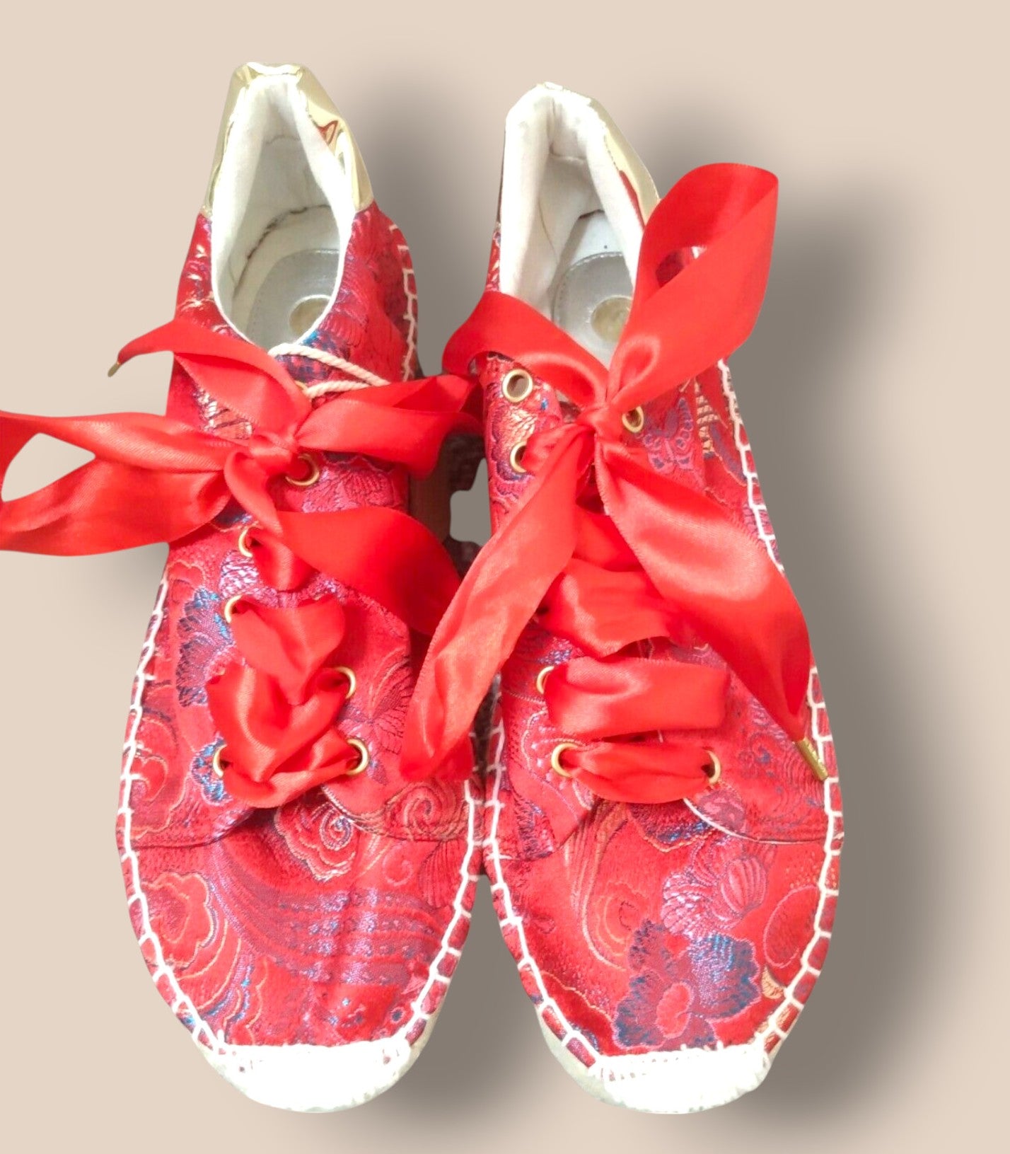 Red sneakers with white laces on a beige background