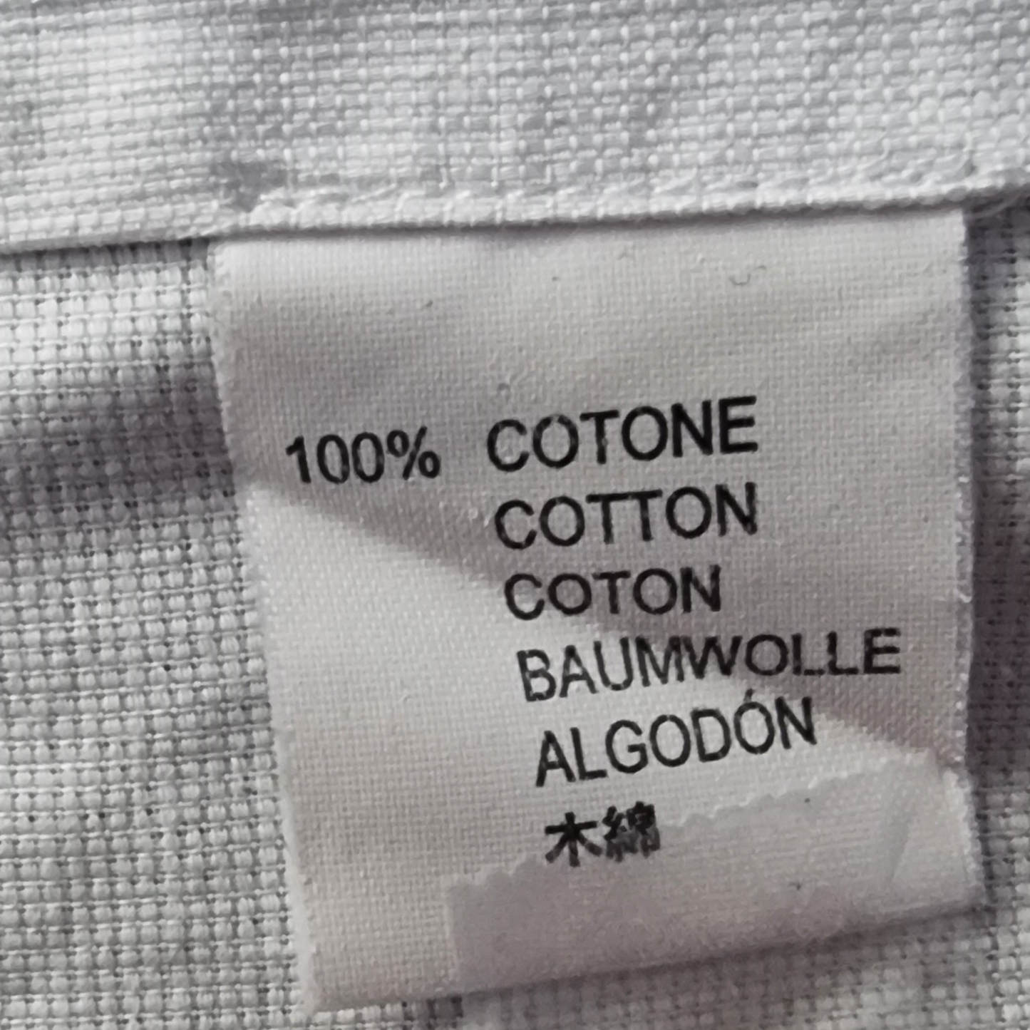 Label on fabric indicating 100% cotton in multiple languages.