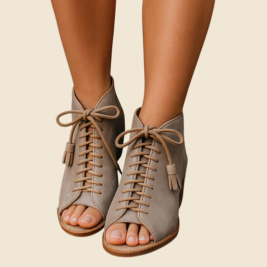 Beige suede open-toe shoes with laces on a beige background