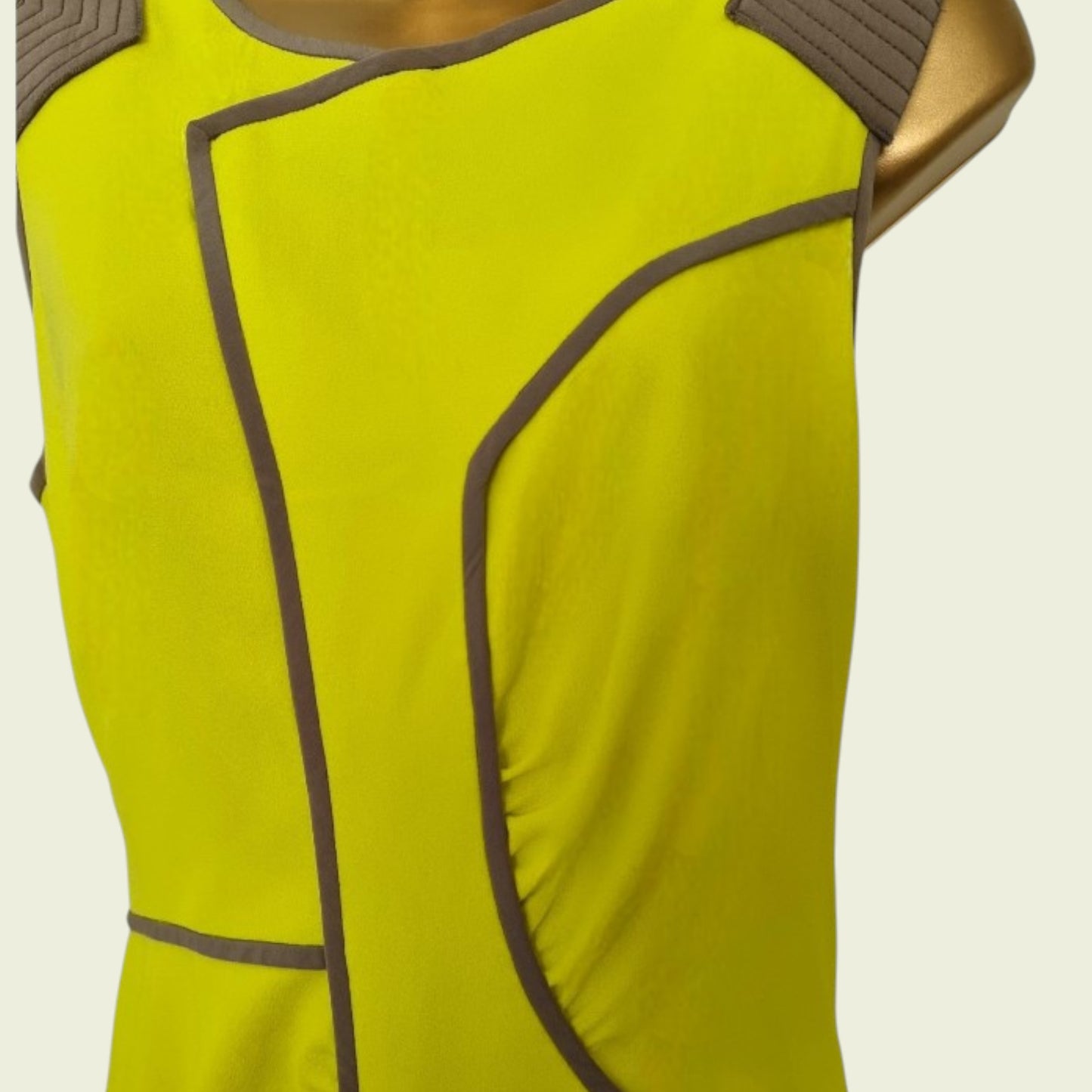 Yellow sleeveless top with brown accents on a beige background