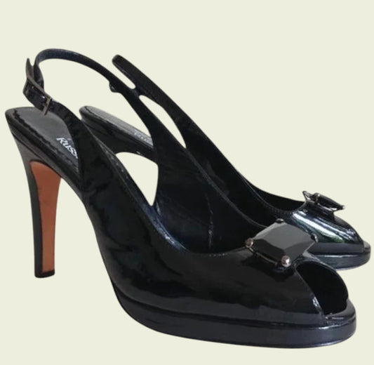 Black high-heeled shoes with a bow detail on a beige background