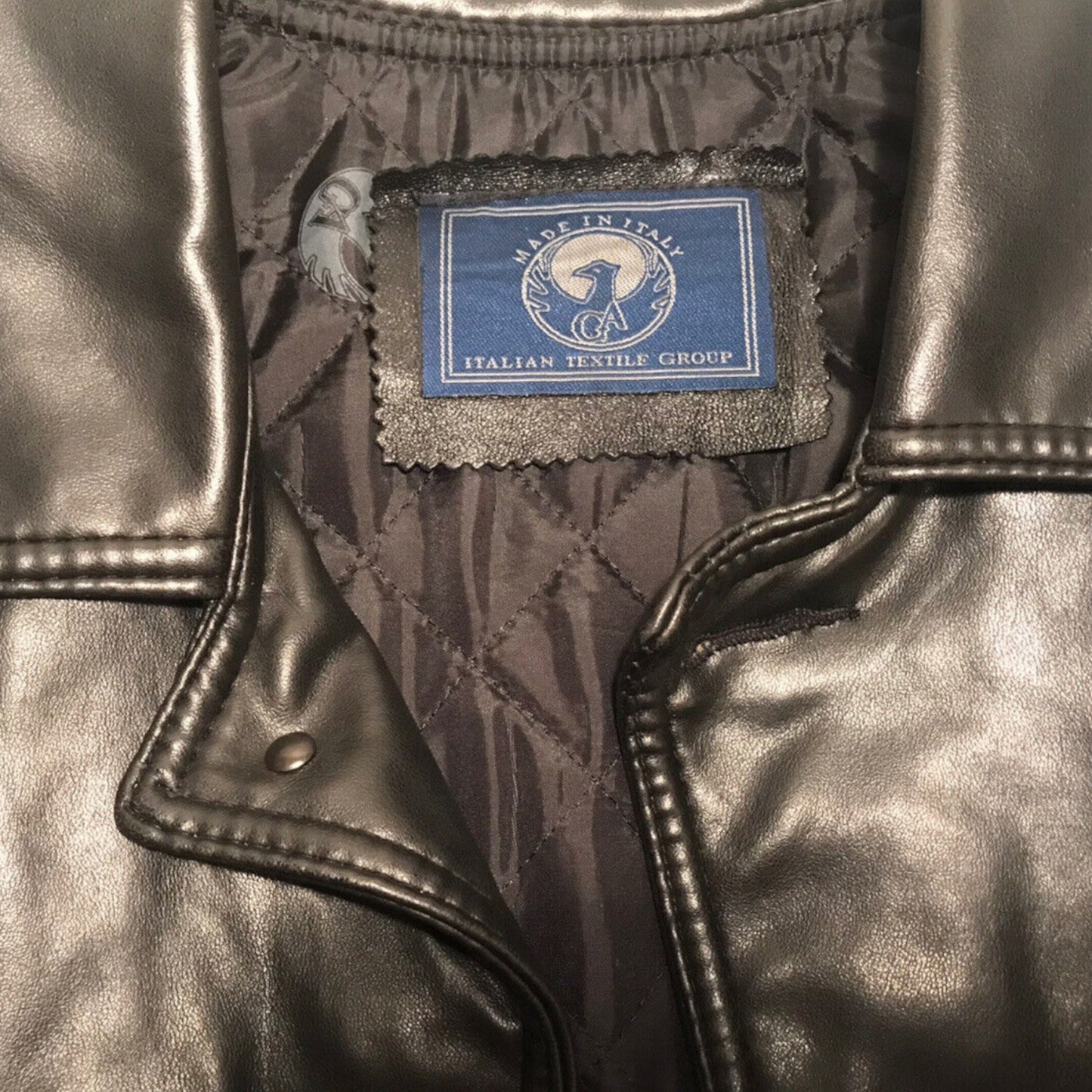 Close-up of a black leather jacket with a blue label on a dark background