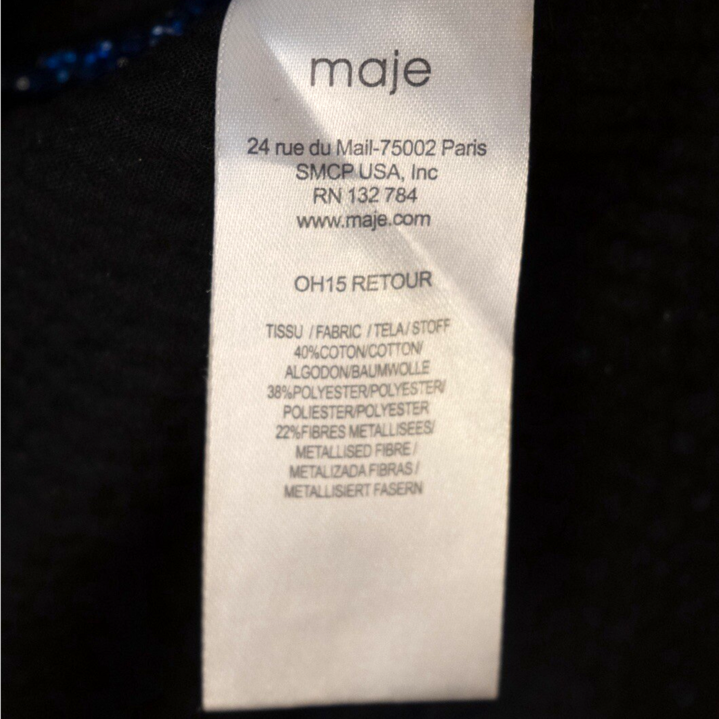 Clothing label with brand name 'maje' and product details on a dark background