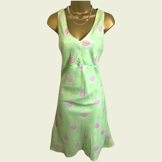 Green dress with pink floral pattern on a mannequin against a white background